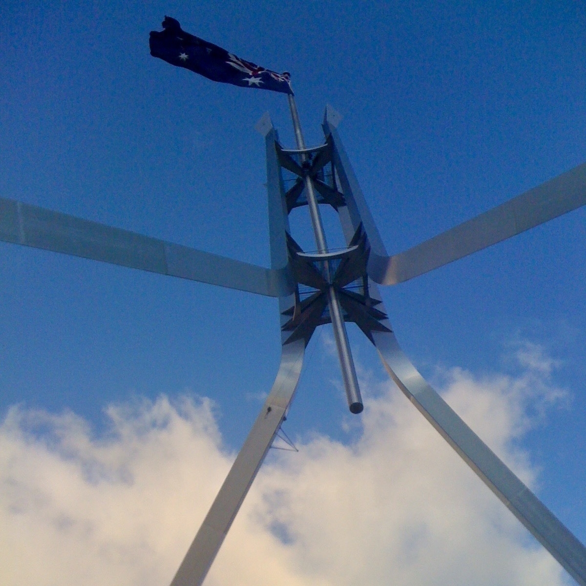 An Australian flag flutters against the blue sky above Canberra's Parliament House