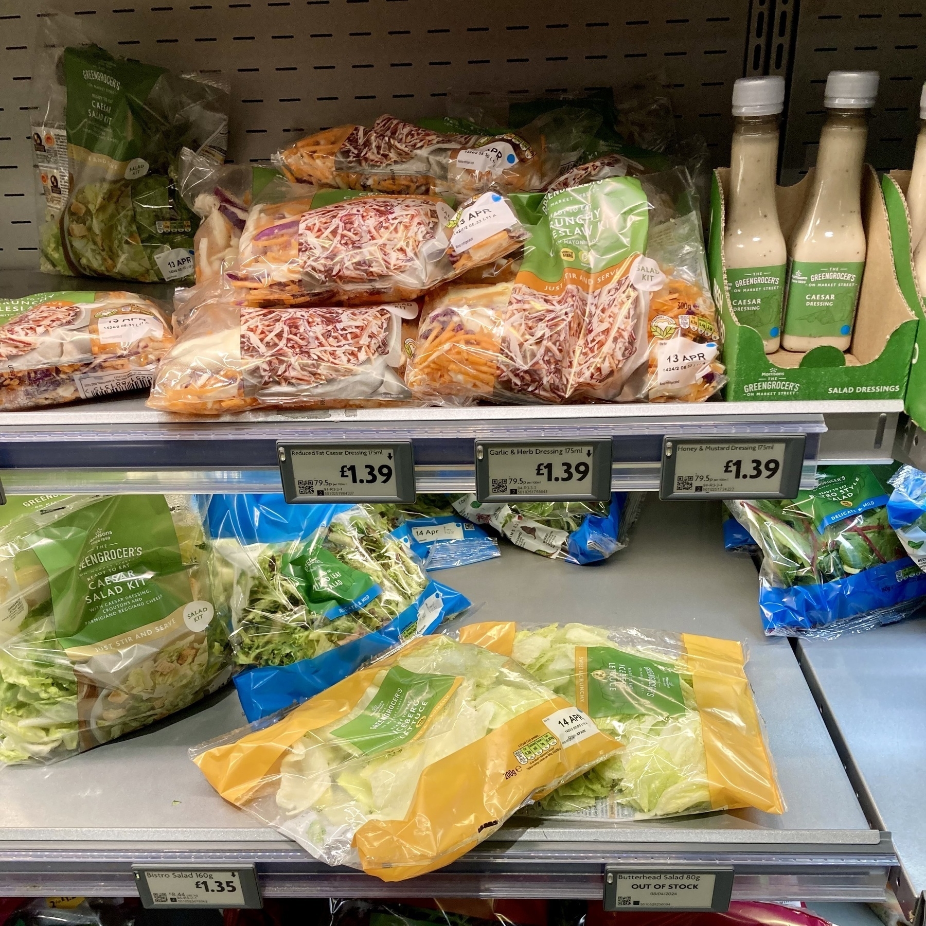 Colourful bags of salad haphazardly on the supermarket shelves
