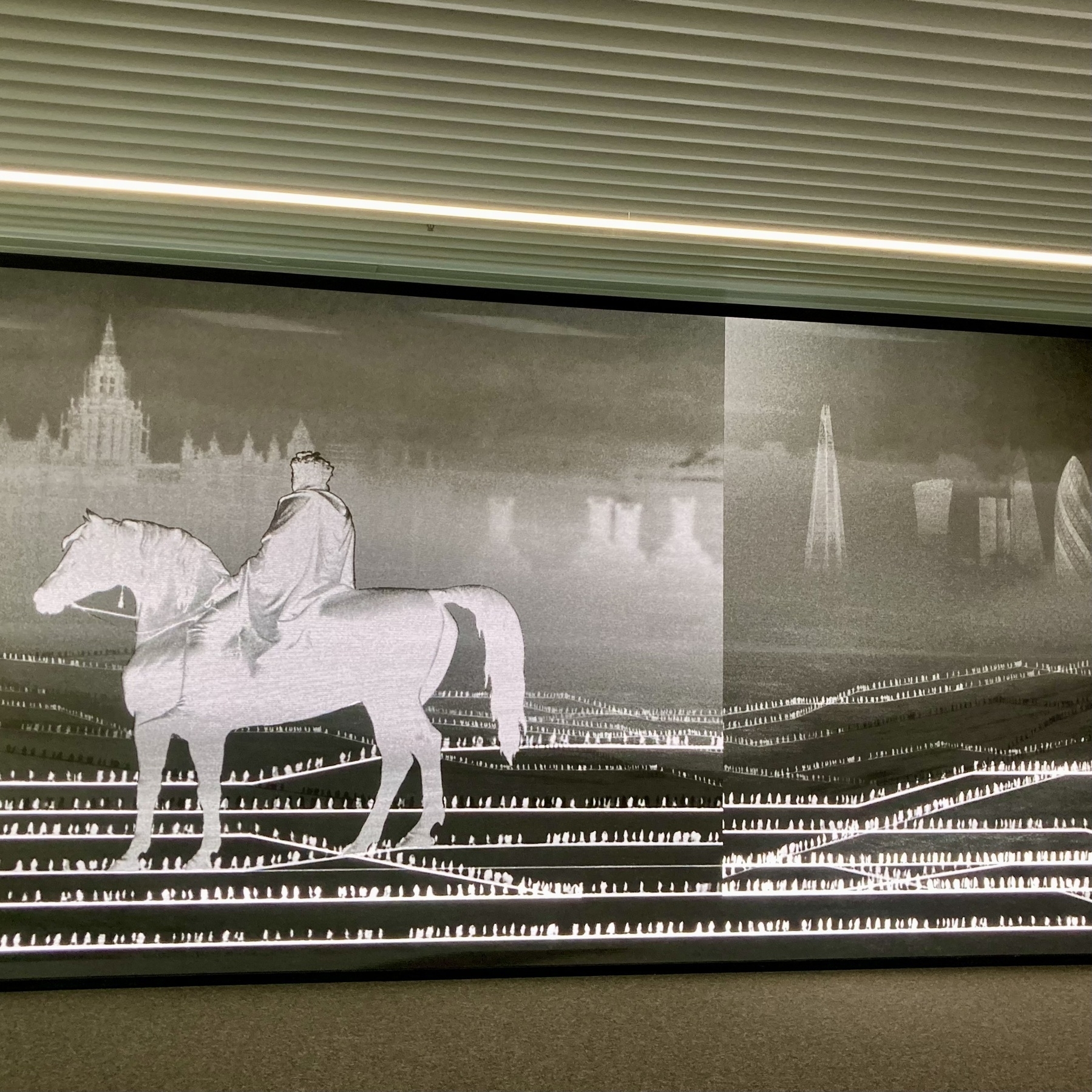 A wall-sized LED displaying a digital artwork at Canary Wharf has developed a glitch with the scene split in the middle - the scene itself is a dreamlike London skyline with small figures whizzing around in invisible Tube trains
