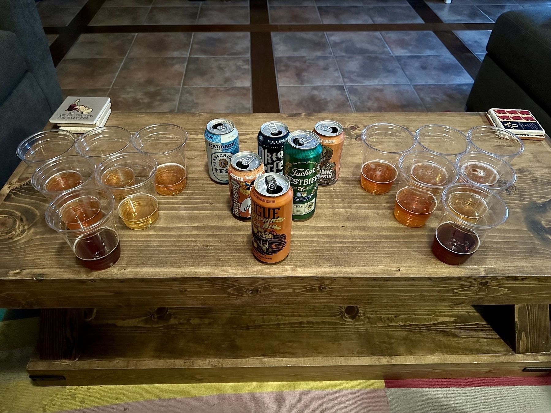 Six cans of beer poured into twelve plastic tasting cups, all arranged in three triangles on a wooden coffee table:&10;&10;* Rogue Pumpkin Patch Ale&10;* Freetail Oktoberfiesta&10;* Tucher Festbier&10;* Karbach Karbachtoberfest&10;* Real Ale Oktoberfest&10;* Voodoo Ranger Atomic Pumpkin&10;&10;&10;