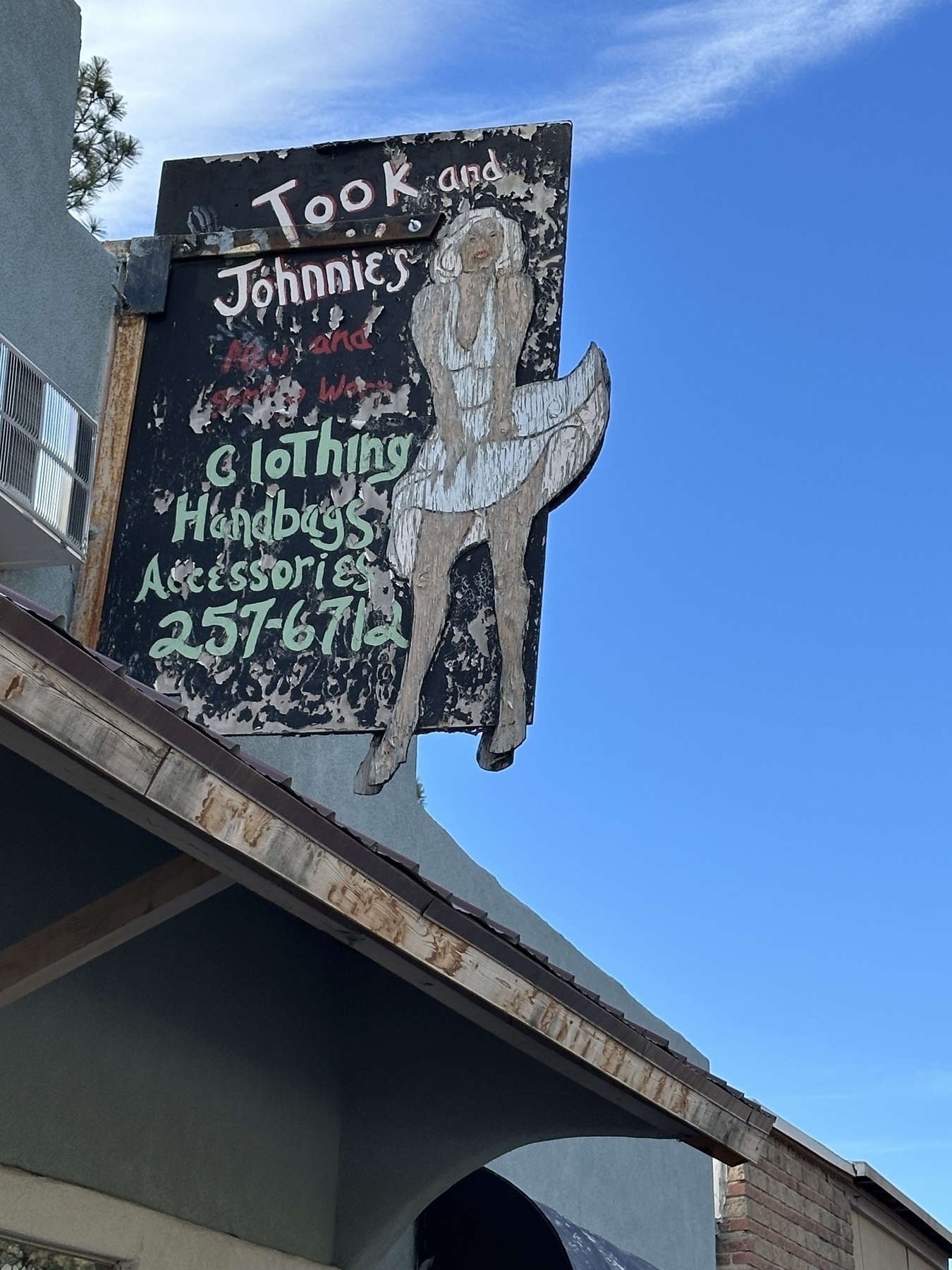 A weathered vintage sign for a store called Took and Johnnie’s features a drawing of Marilyn Monroe’s subway grate pose.