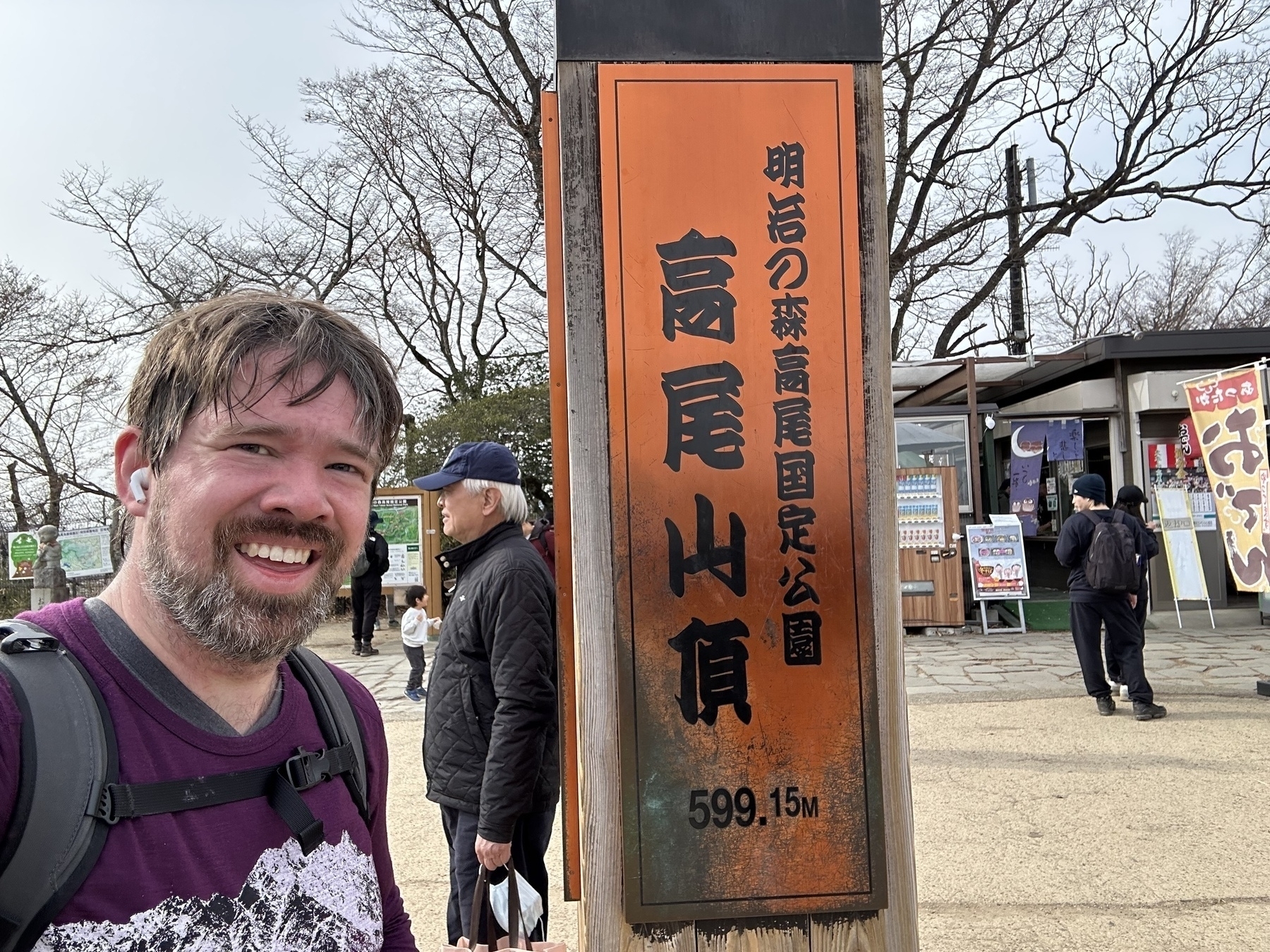 Selfie next to a bronze plaque taller than me indicating the height of the peak, 599.15 meters