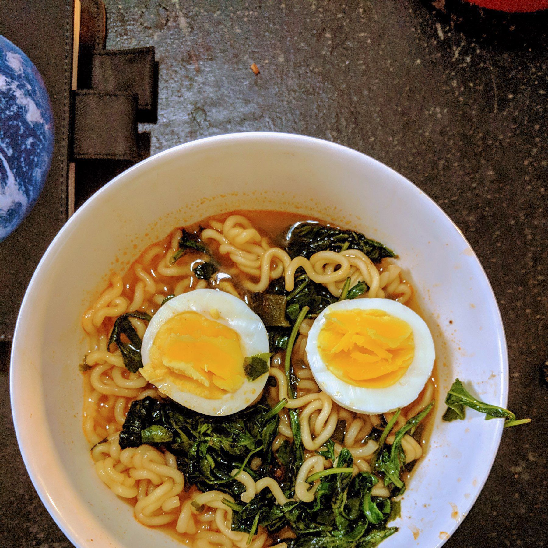 Ramen noodles in spicy broth with arugula and face up hardboiled egg