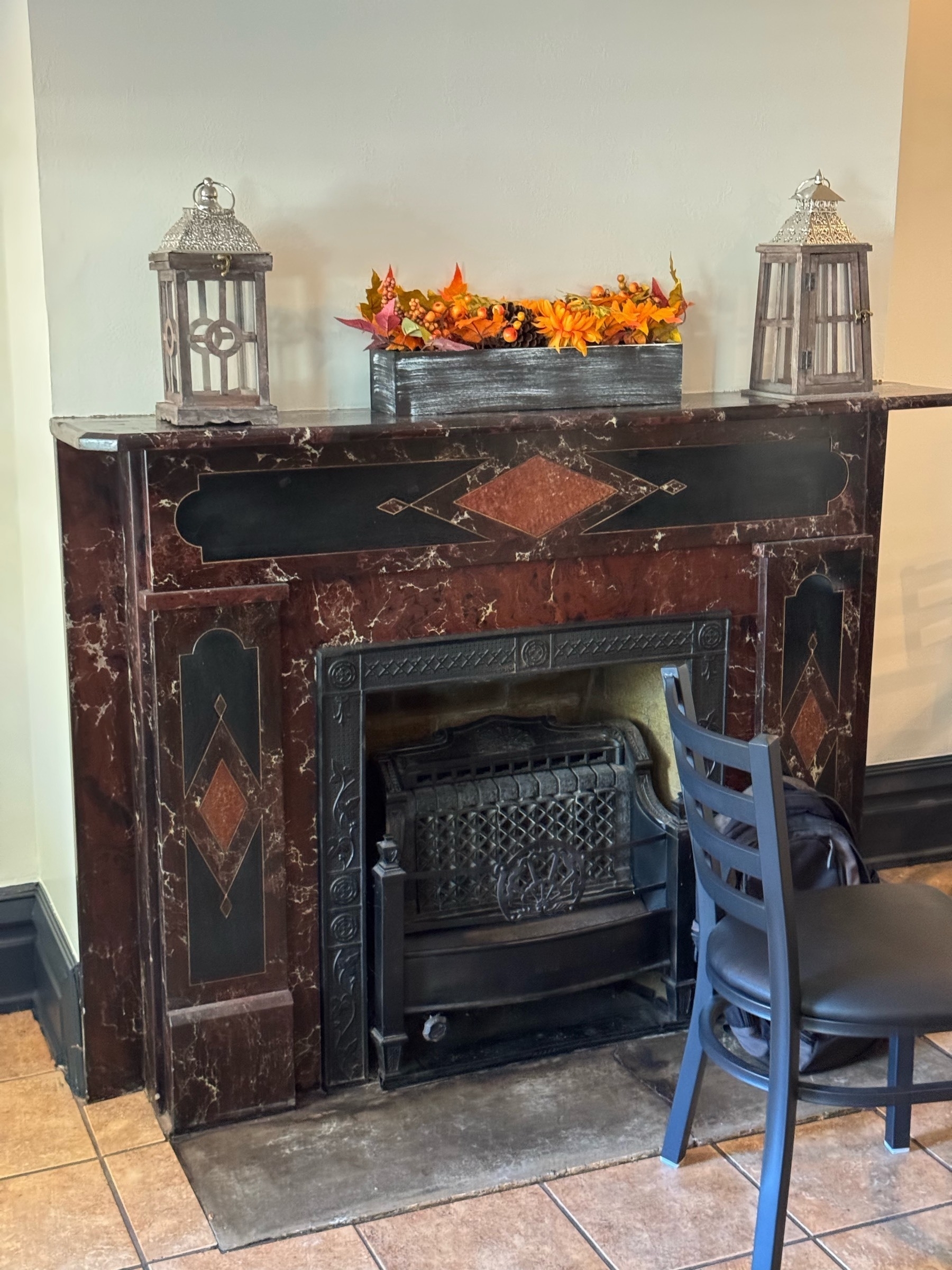 Old dark wooden fireplace with two glass lanterns on the mantle 