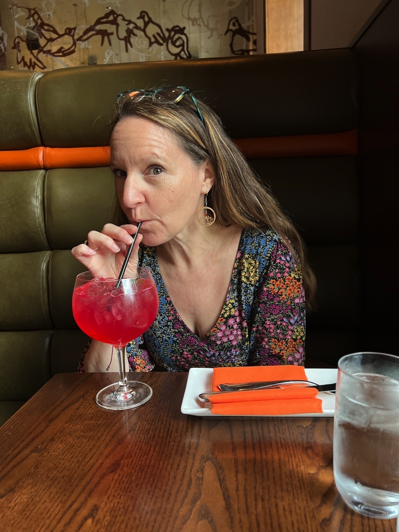 woman sipping a cocktail in a restaurant booth