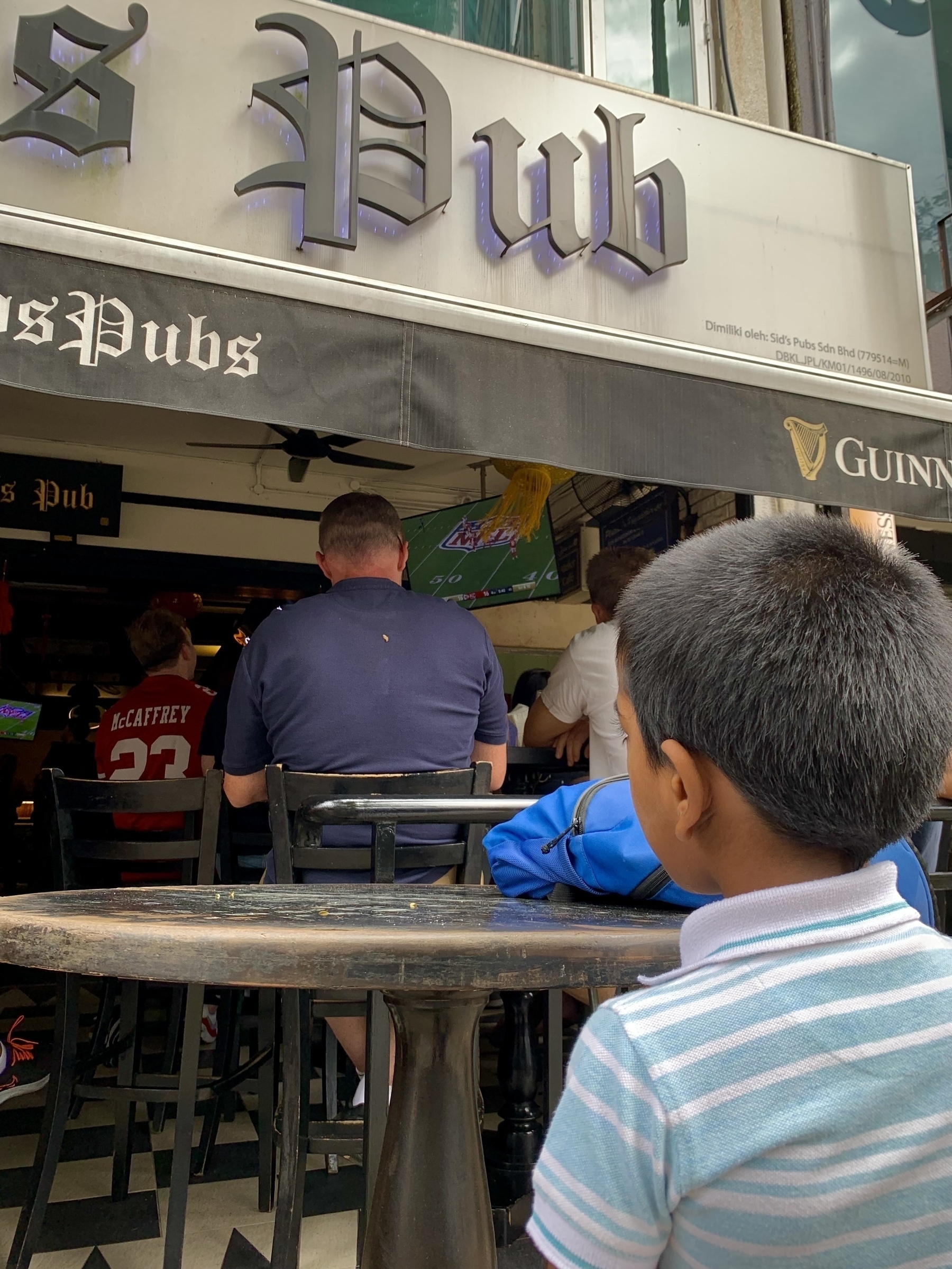 Little boy watching Super Bowl 2024 at a pub. 