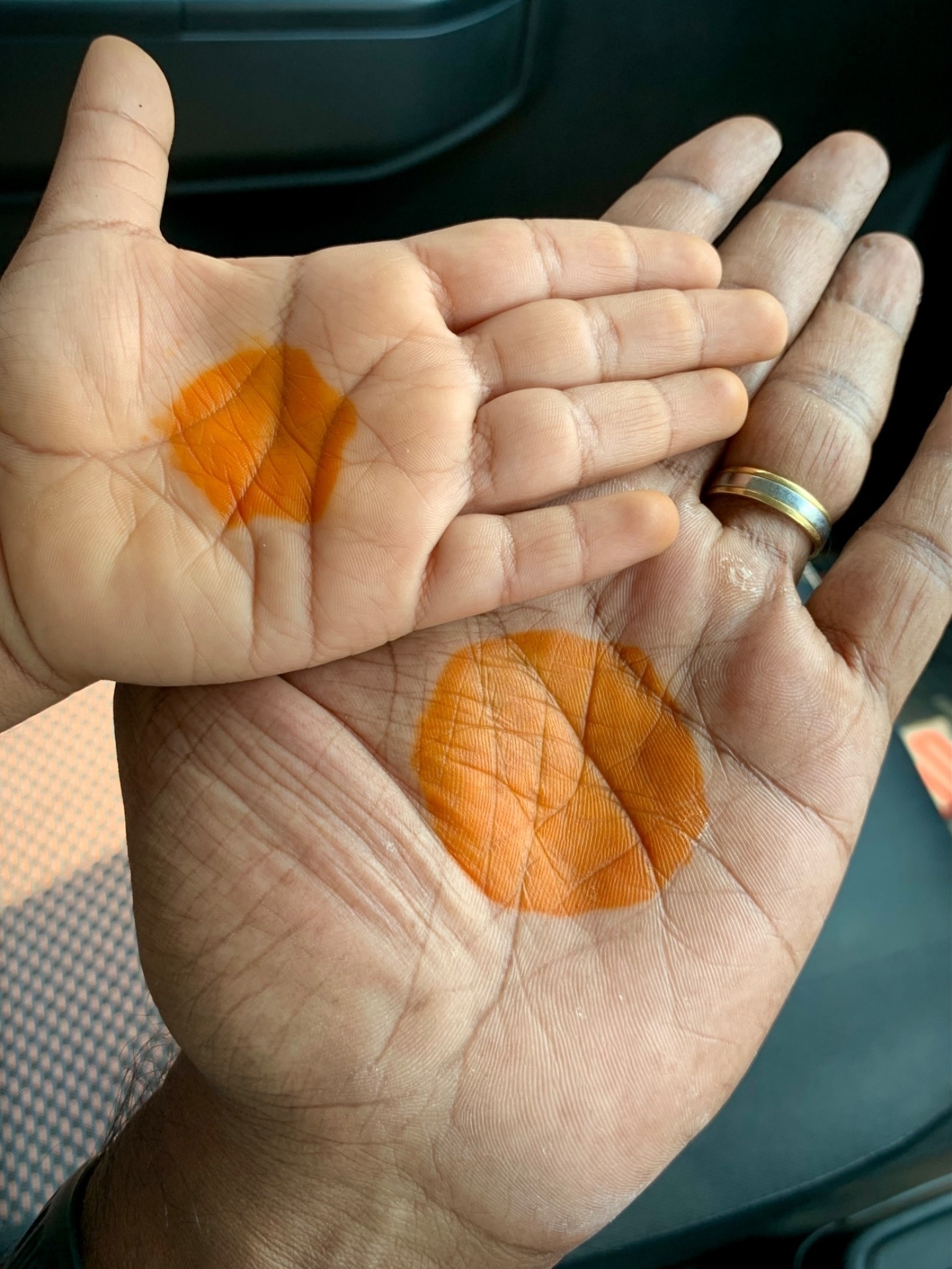 Two hands, one larger than the other, have circular henna designs on their palms.