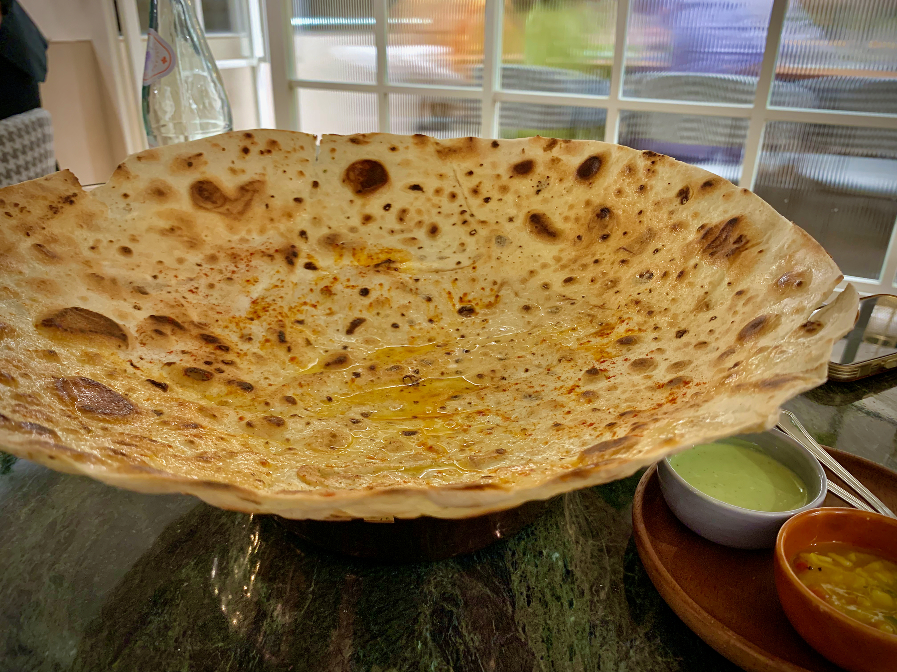 Kadak Roomali Roti, a crisp wafer thin bread topped with melted butter and spice powders.