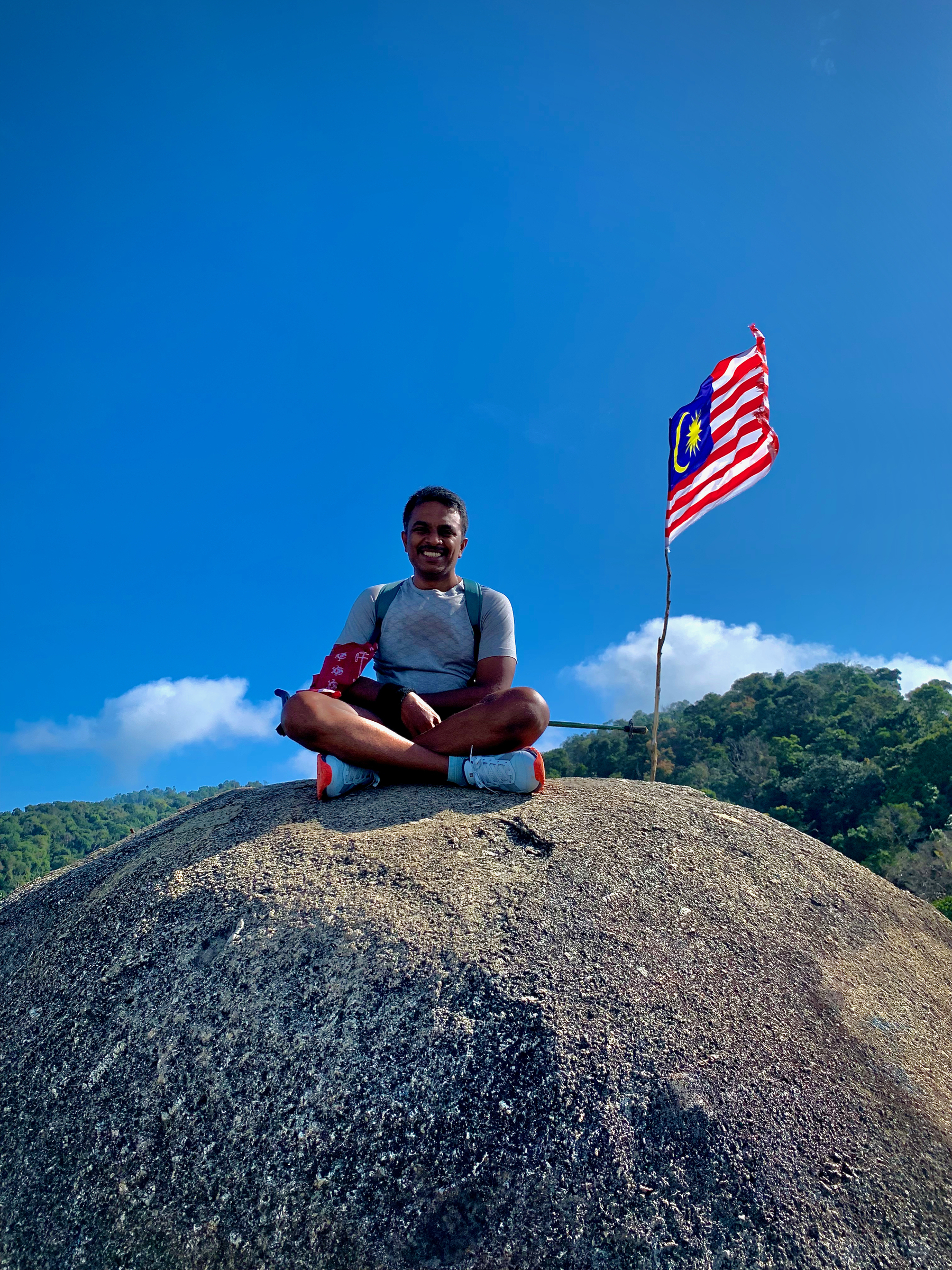 A man atop a rock at the summit of Gunung Datuk