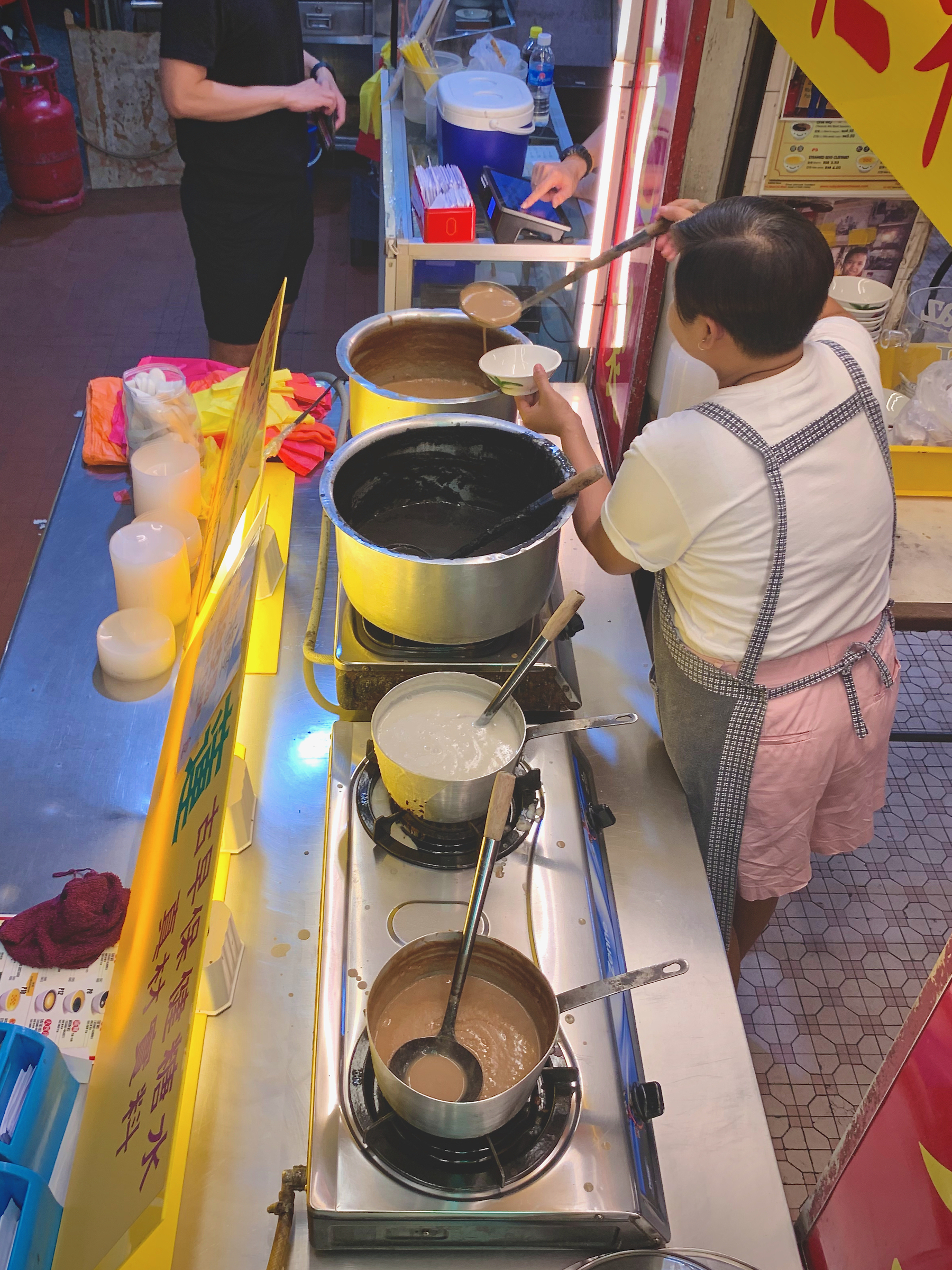 A man tending to the warm pots of desserts