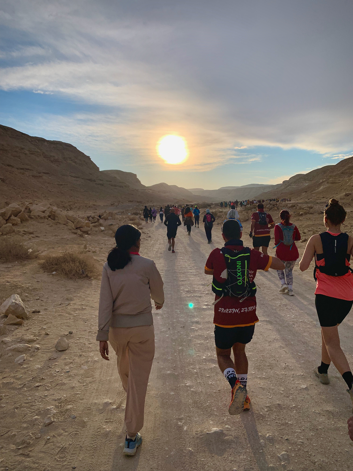 Trail runners starting off the run towards the valley with the sun rising in front of them.