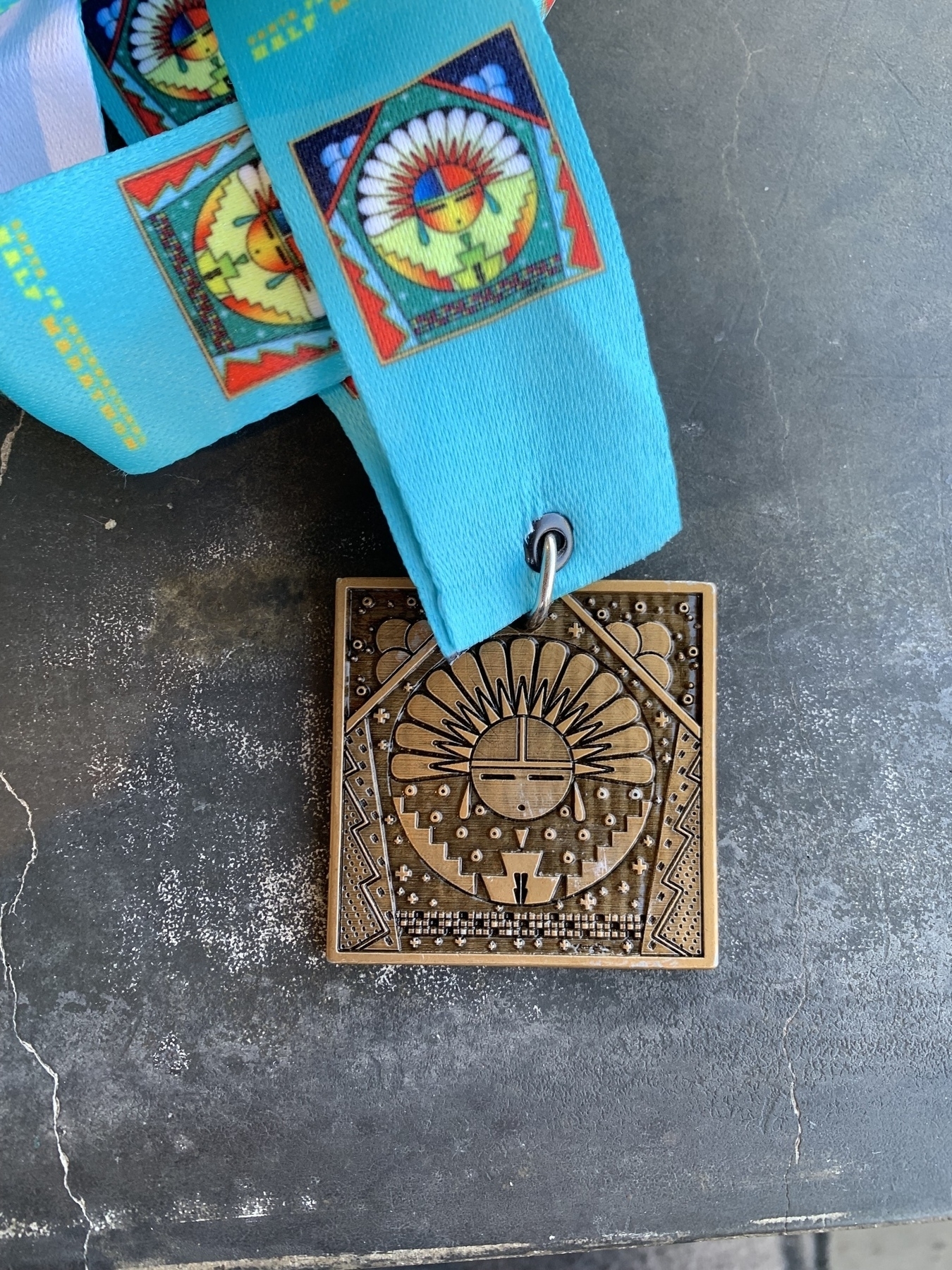Sun face insignia on medal with turquoise lanyard
