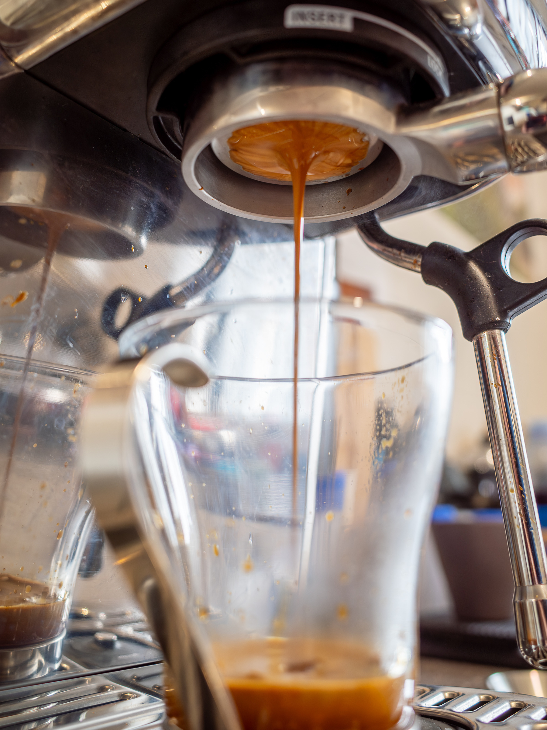 Extraction of espresso coffee into a glass mug.