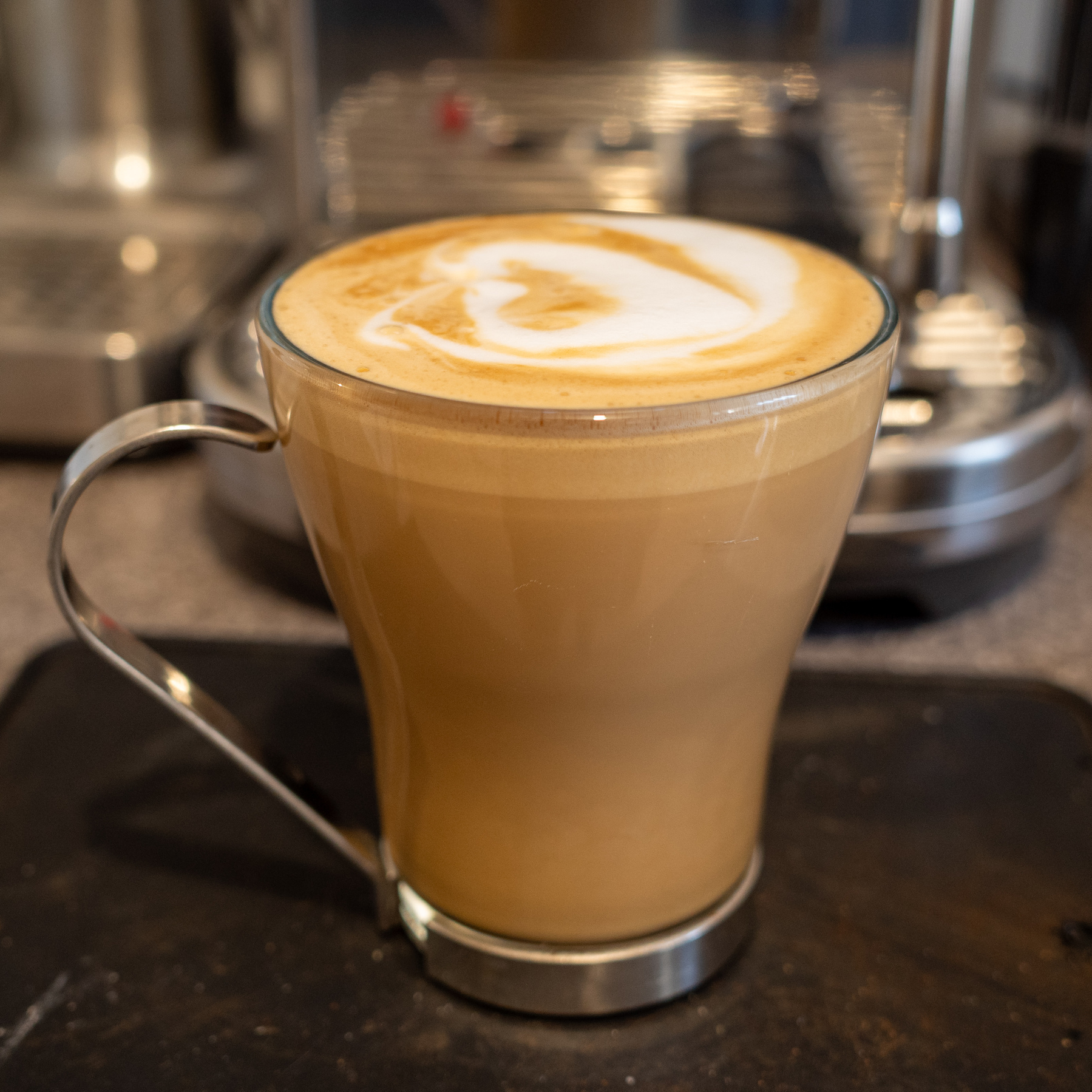 Flat white coffee in a glass mug.