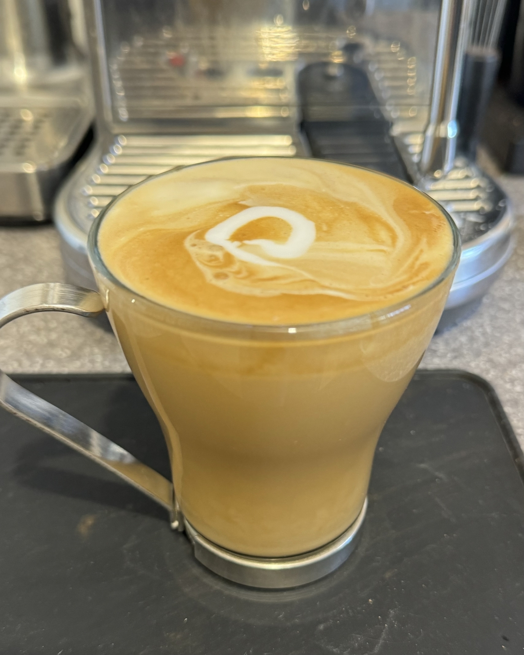 A flat white coffee in a glass mug