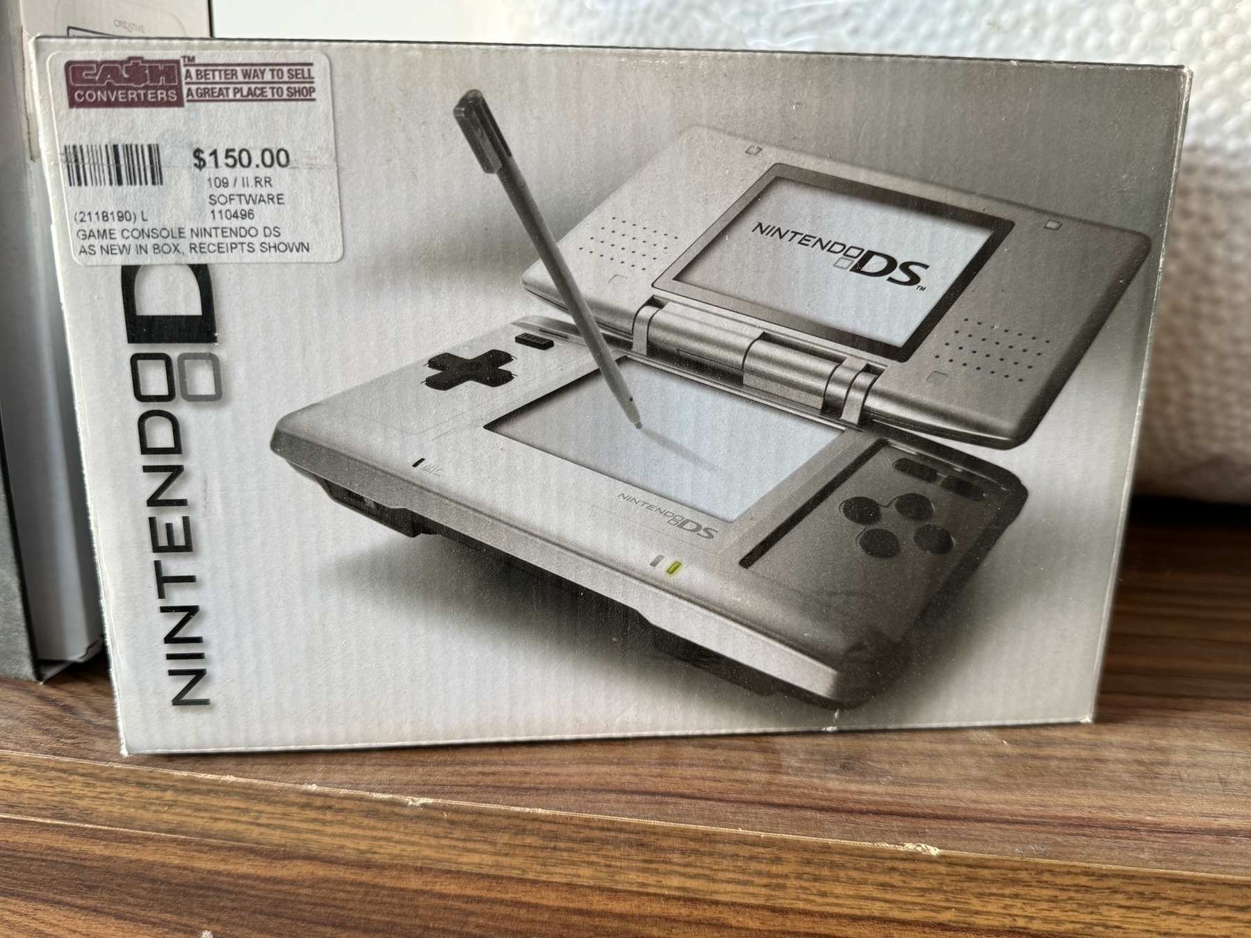 A box of an original Nintendo DS from 2004 with a Cash Converters price sticker on it.