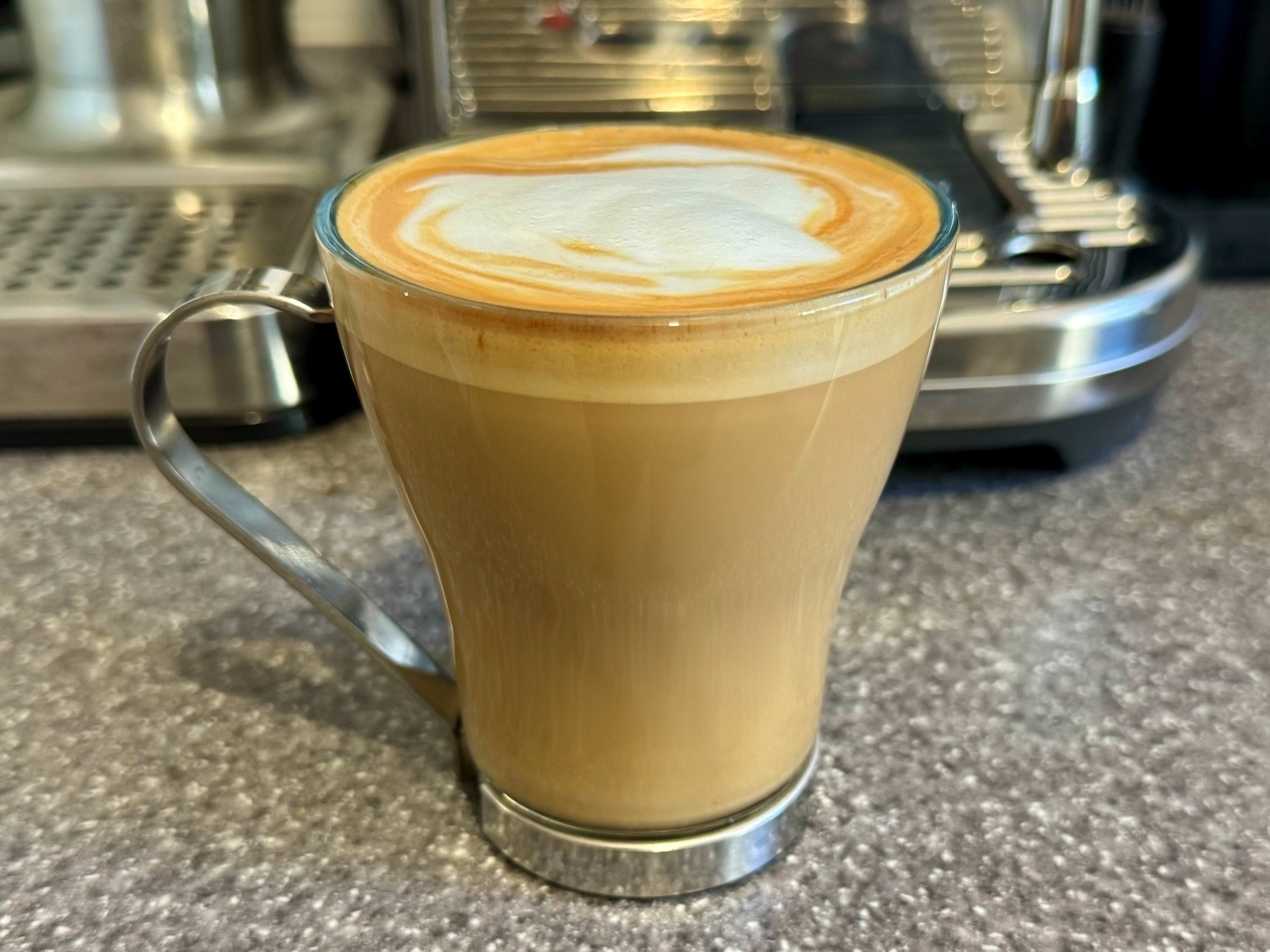 Flat white coffee in a glass mug.