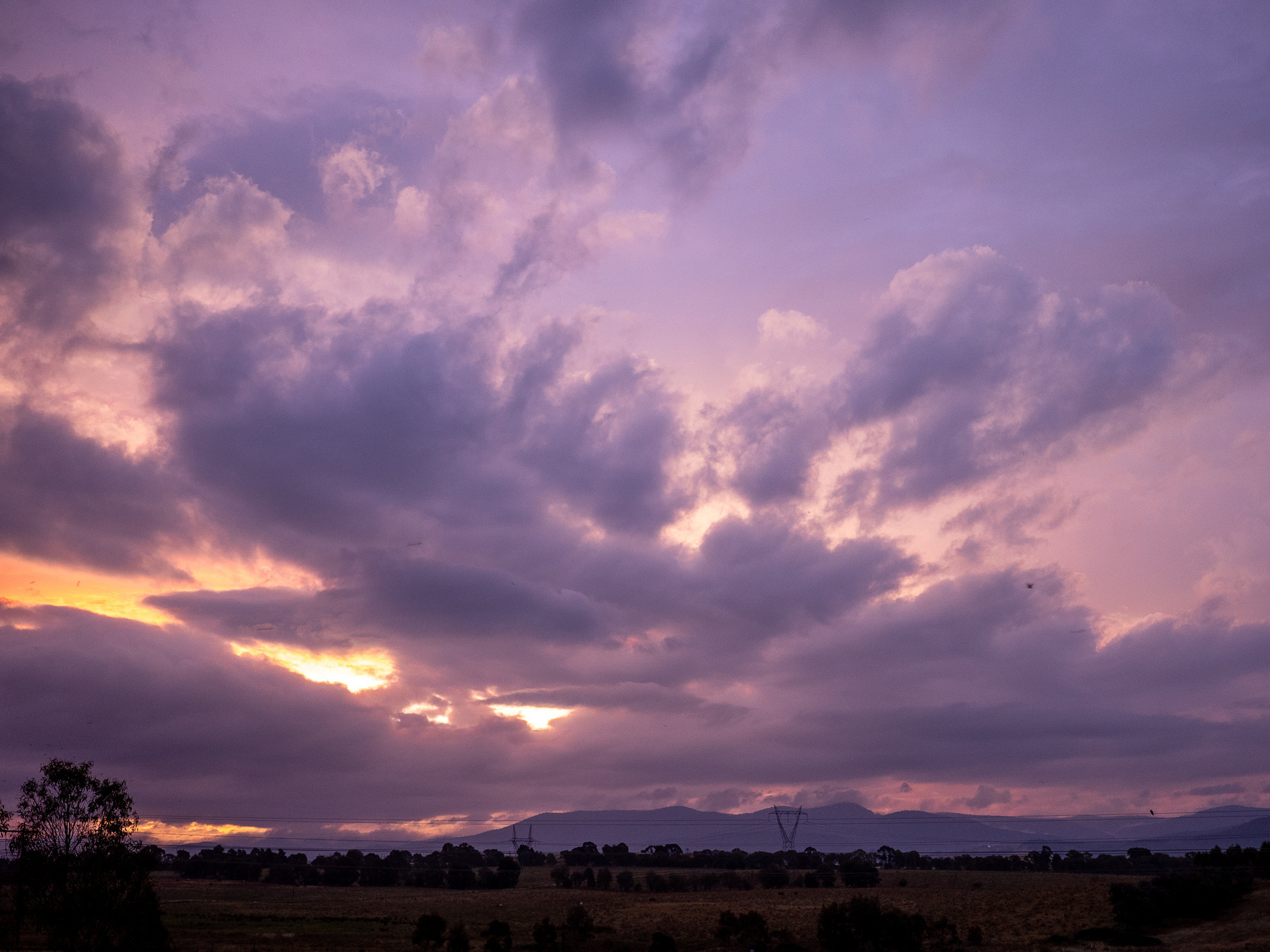 A sunset behind layers of purple clouds.