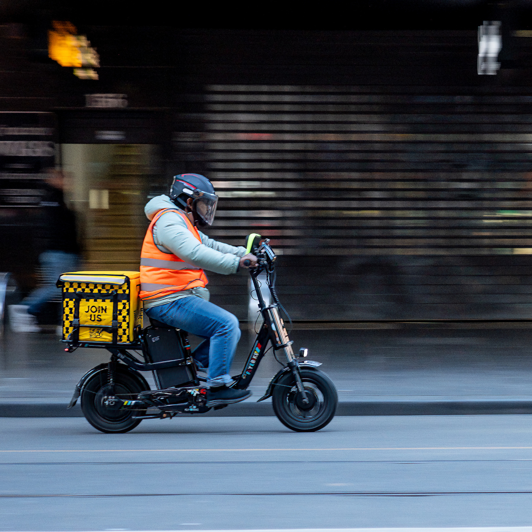 A delivery rider on an electric scooter, wearing hi-vis