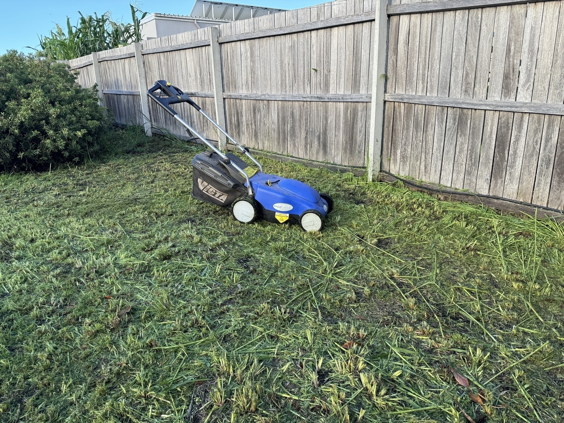 All done! Electric lawnmower sitting on the ground.