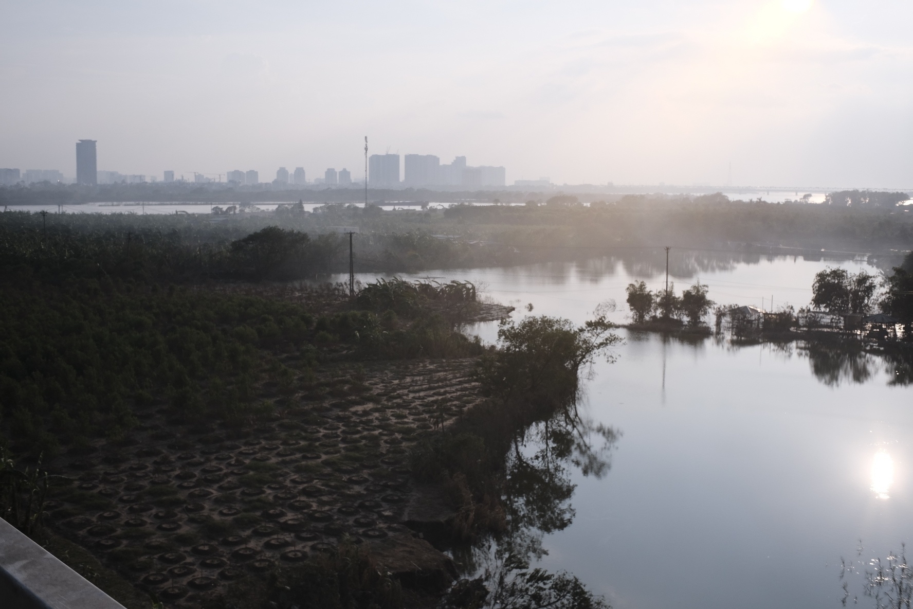 You see the red river in Hanoi from a highway bride, sun in the background. It's quite beautiful. But a closer look reveals the fact that half of the water is in areas where it should not be, covering agricultural and some houses. A storm just destroyed everything 