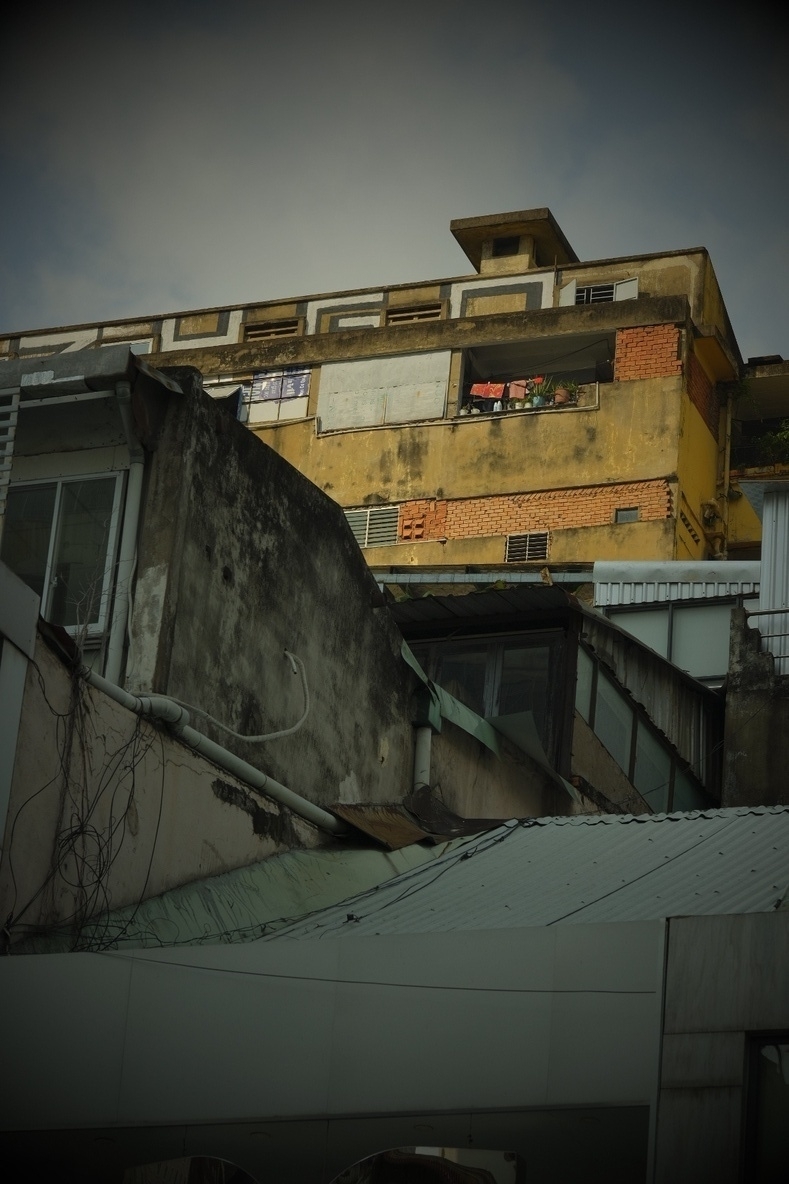 Early morning shot from typical Vietnamese buildings stacked on top of each other. A washed off, yellowish concrete block is illuminated by the sun. Clothes are drying outside 