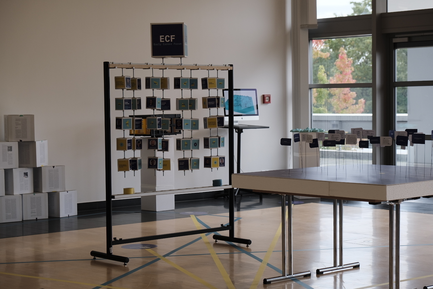 Snapshot from an exhibition, you see the contributors to a book on a playful device, every author is a cube