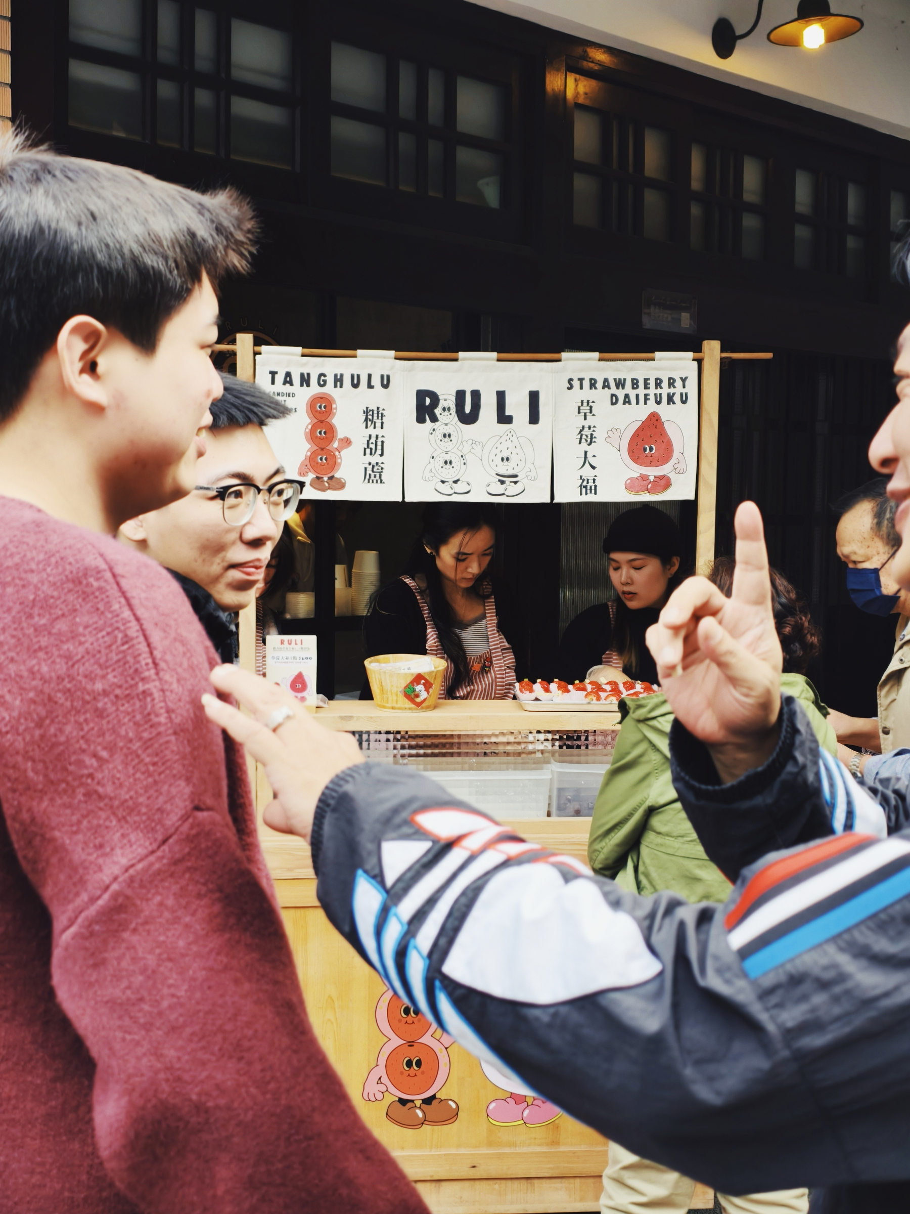 3 men in front of a street food shop, where many people are queuing (not on the picture). 