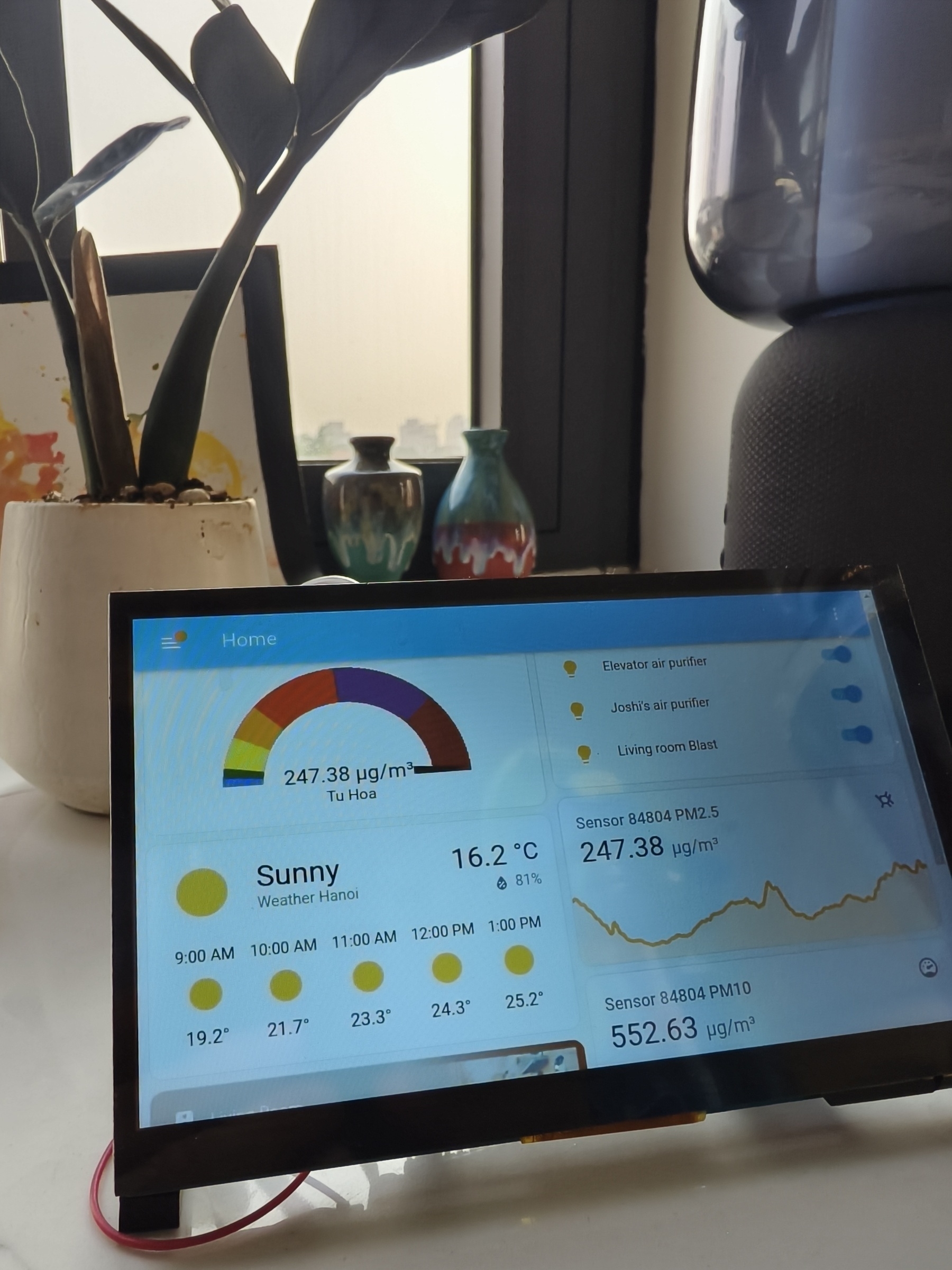 Snapshot of an home automation system which displays data from air sensors outside, weather data and a management system for indoor air filters, all turned on and on max. Pi-powered.&10;&10;It's sunny, you see here, but outside is not sun in sight. That's related to the high PM 2.5 numbers recorded on the screen, 247 µg/m³ aka an AQI of roughly 500. &10;&10;In the background of the screen is a flower and a window, where you can sense the grey air.