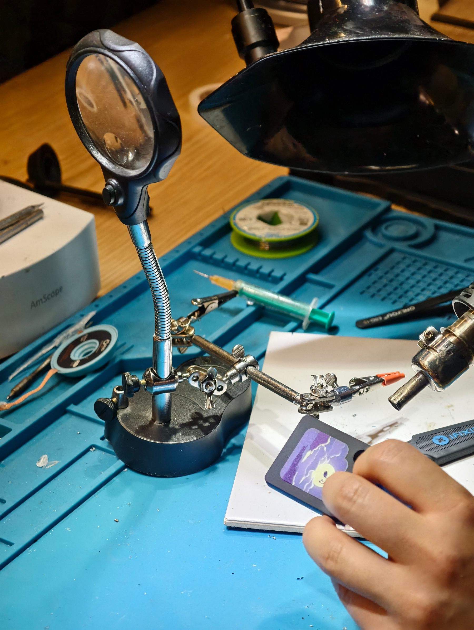 Using a bunch of tools to open a little plastic token that functions as a tape for a "Galakto" audio box. These magnetically attach on top of these little boxes. Very easy to use. This is the setting of a makerspace with iFixit tools and more. Colorful