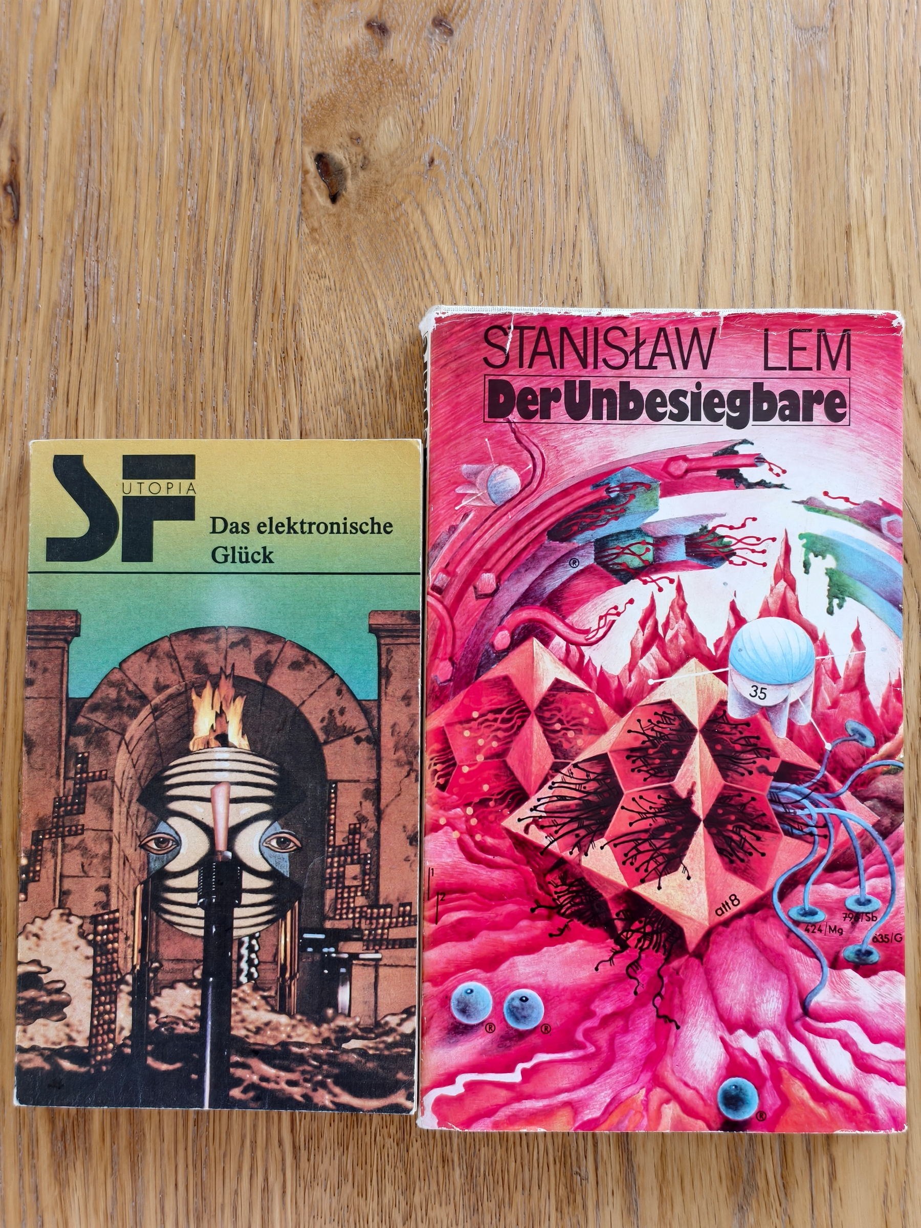 Stanislaw Lems Unbesiegbare und eine Anthologie zum Elektronischen Glück, zwei Bücherfunde mit bunten Covern auf einem Holztisch