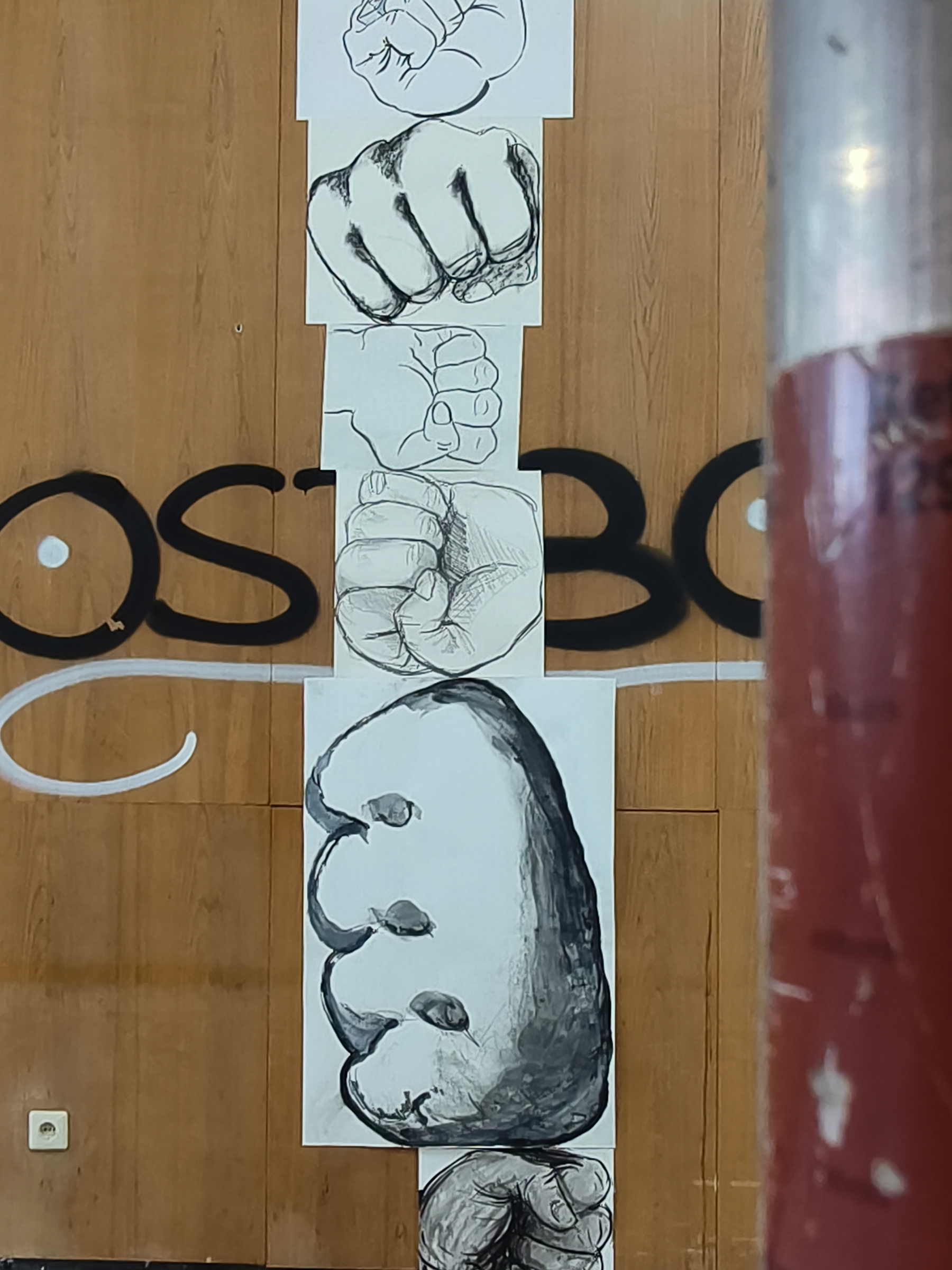 Unterschiedliche Zeichnungen von Fäusten vor einer Holzwand, Teil der Ausstellung über die Kunstausstellungen der DDR