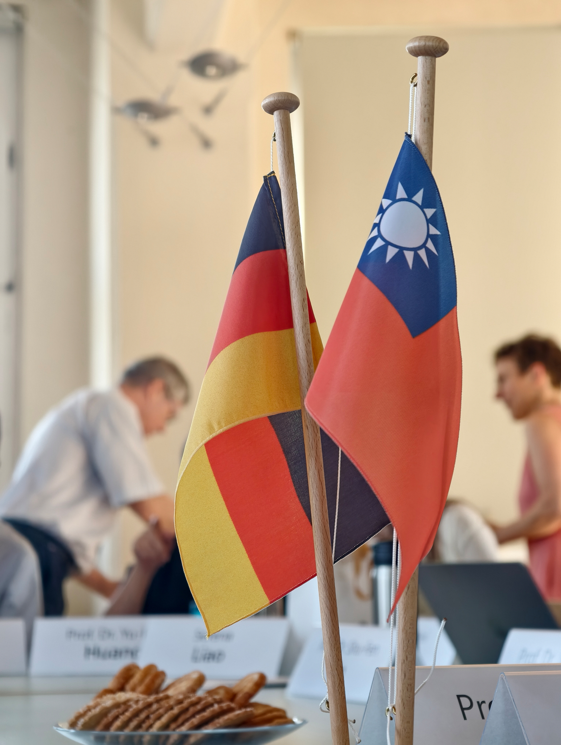 Snapshot of the German and Taiwan flags that reside in the middle of a table, snacks nearby 