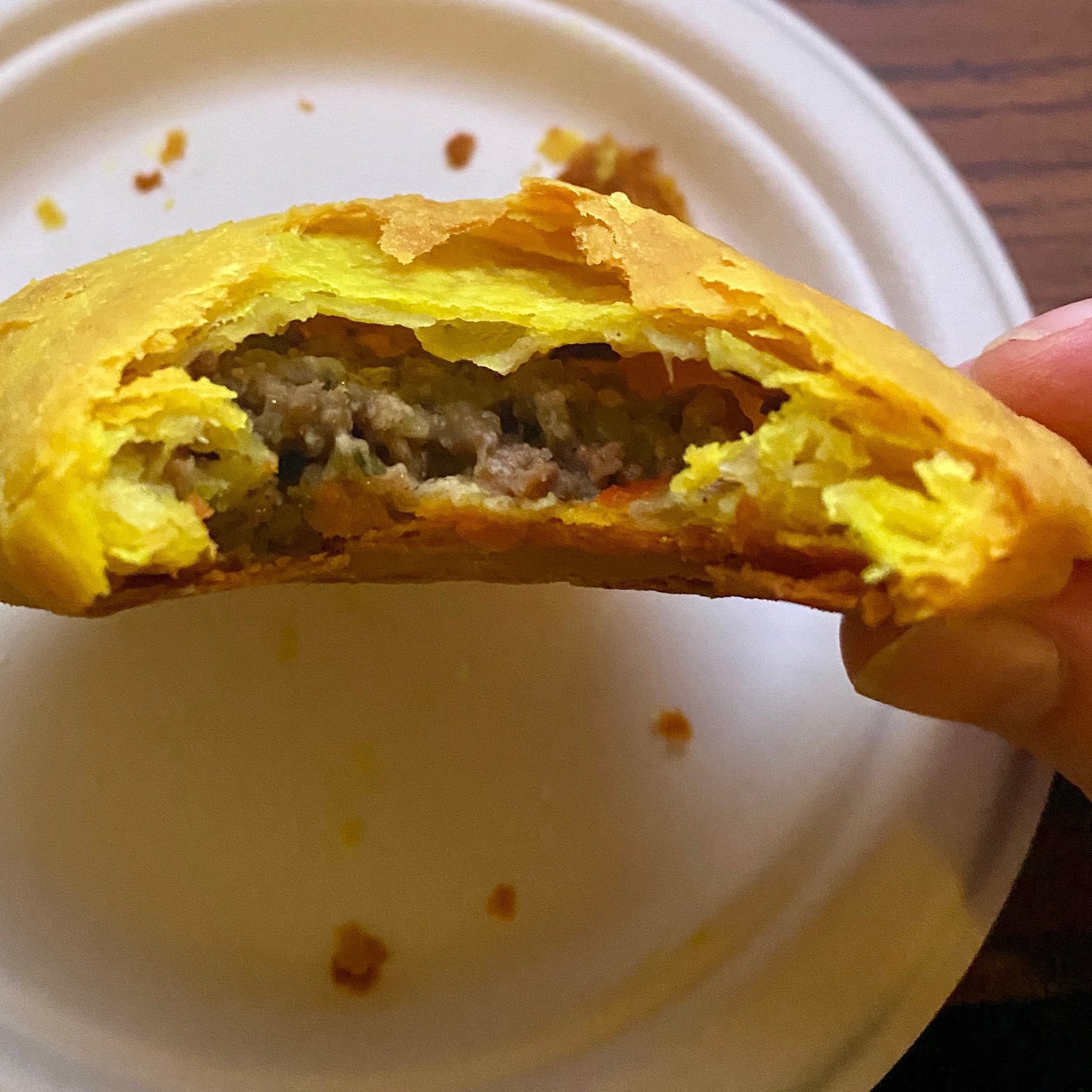 Photo of homemade beef patty with bite take out of it, showing flaky crust. 