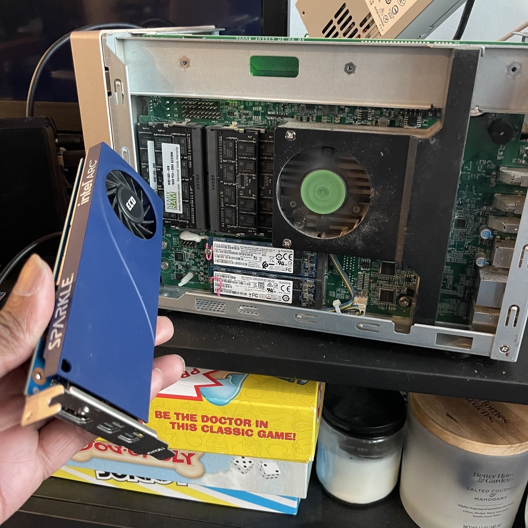 A person is holding a SPARKLE graphics card next to an open NAS computer with visible internal components.