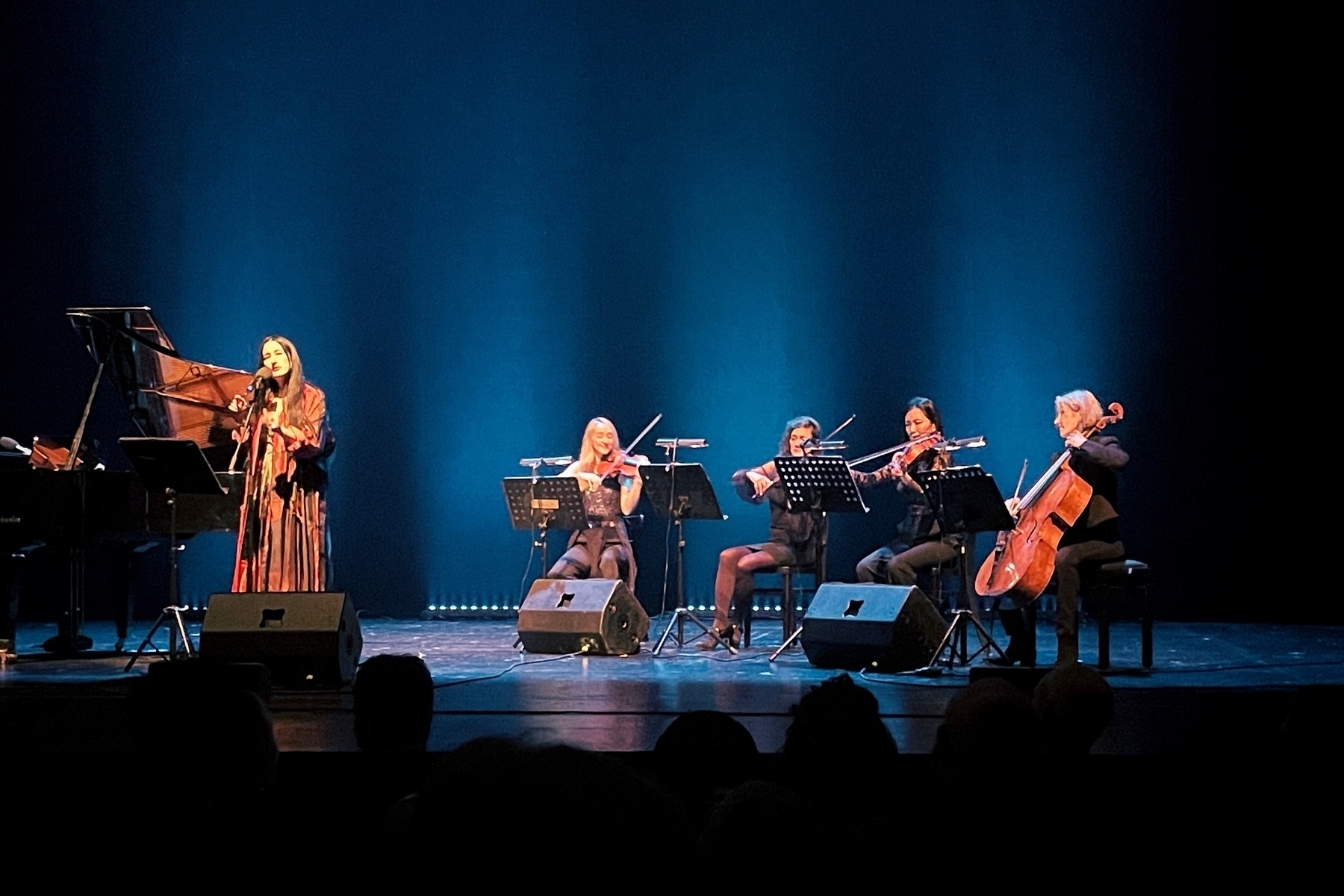 Stage, Zola Jesus on the left standing and singing, on the right three sitting violin players and a cellist 