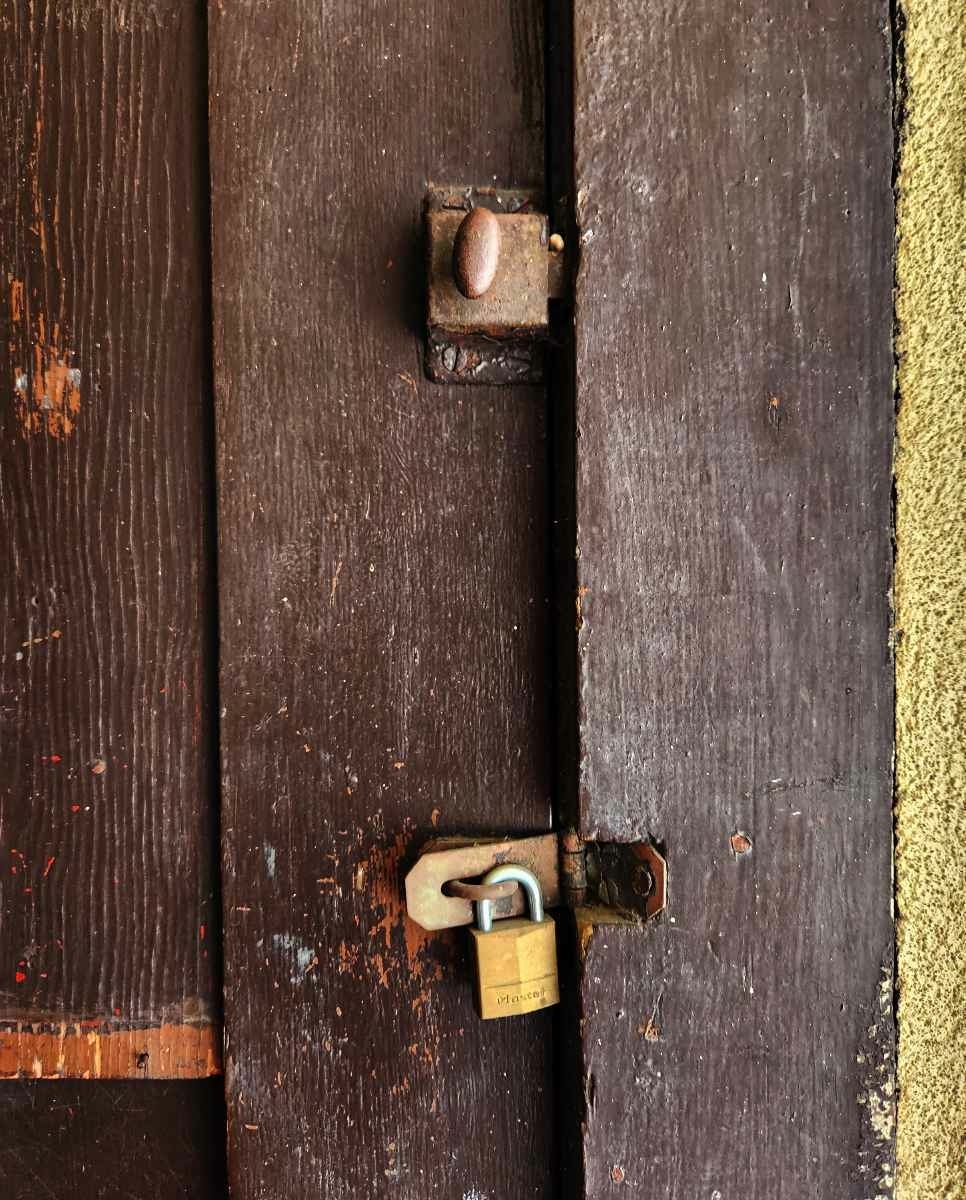 Old wooden hatch with brass doorknob and padlock