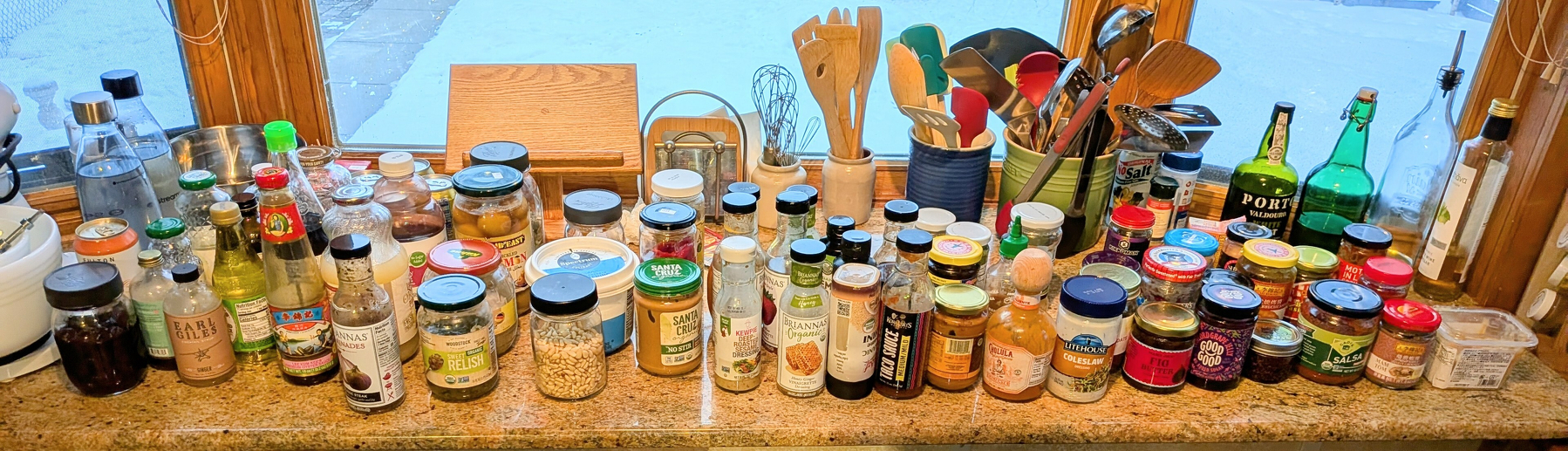 Wide view of a counter lined with many bottles and jars of food items.