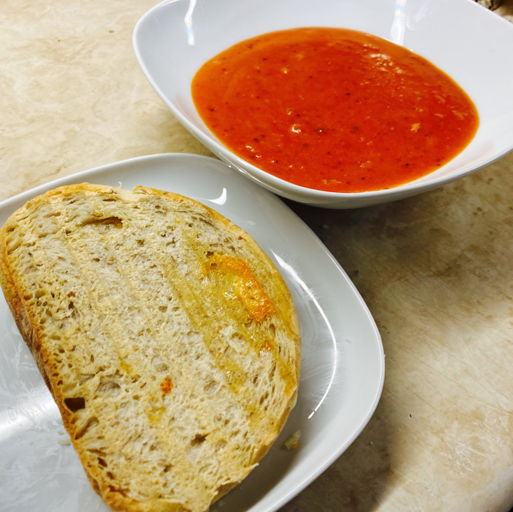 Grilled cheese sandwich on plate and bowl of tomato soup.