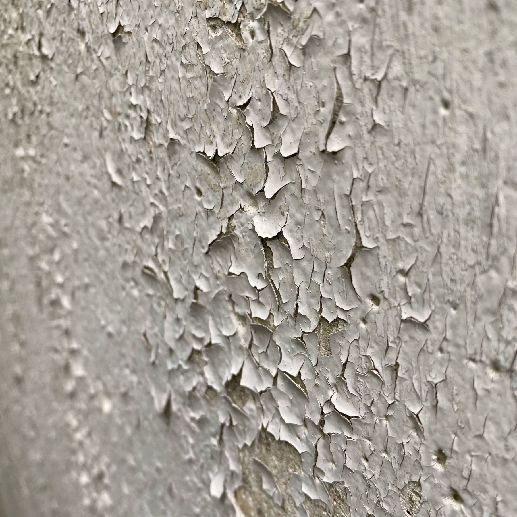 Paint flaking on concrete wall.