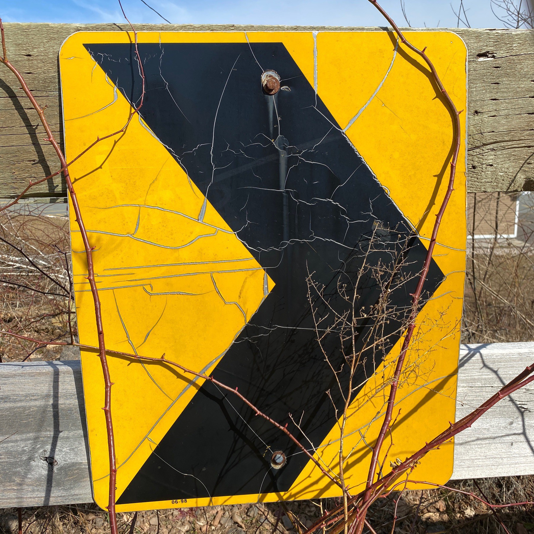 Arrow on sign on wooden fence.