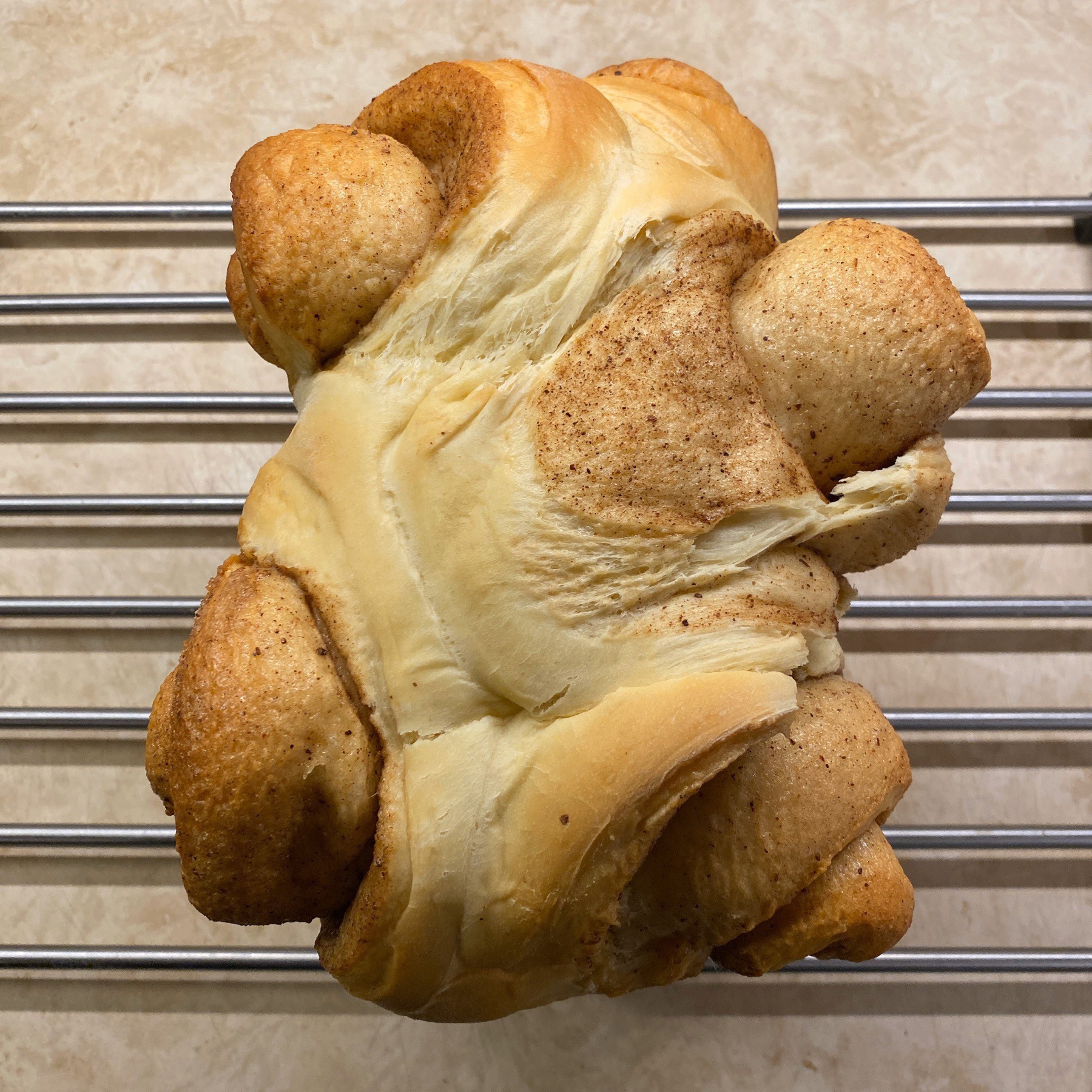 Cinnamon bun bread loaf cooling on rack.