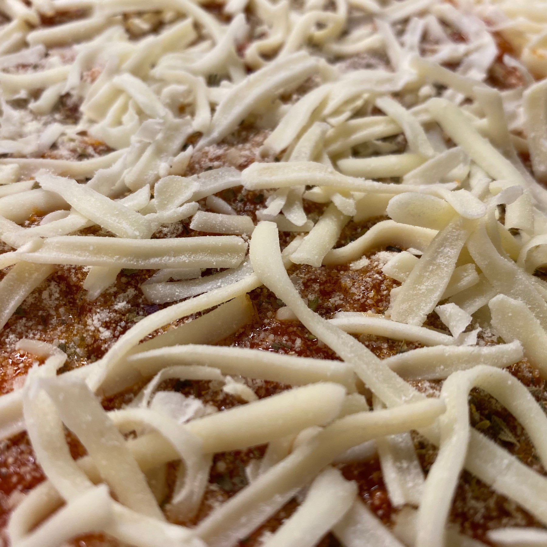 Cheese on pizza before baking.