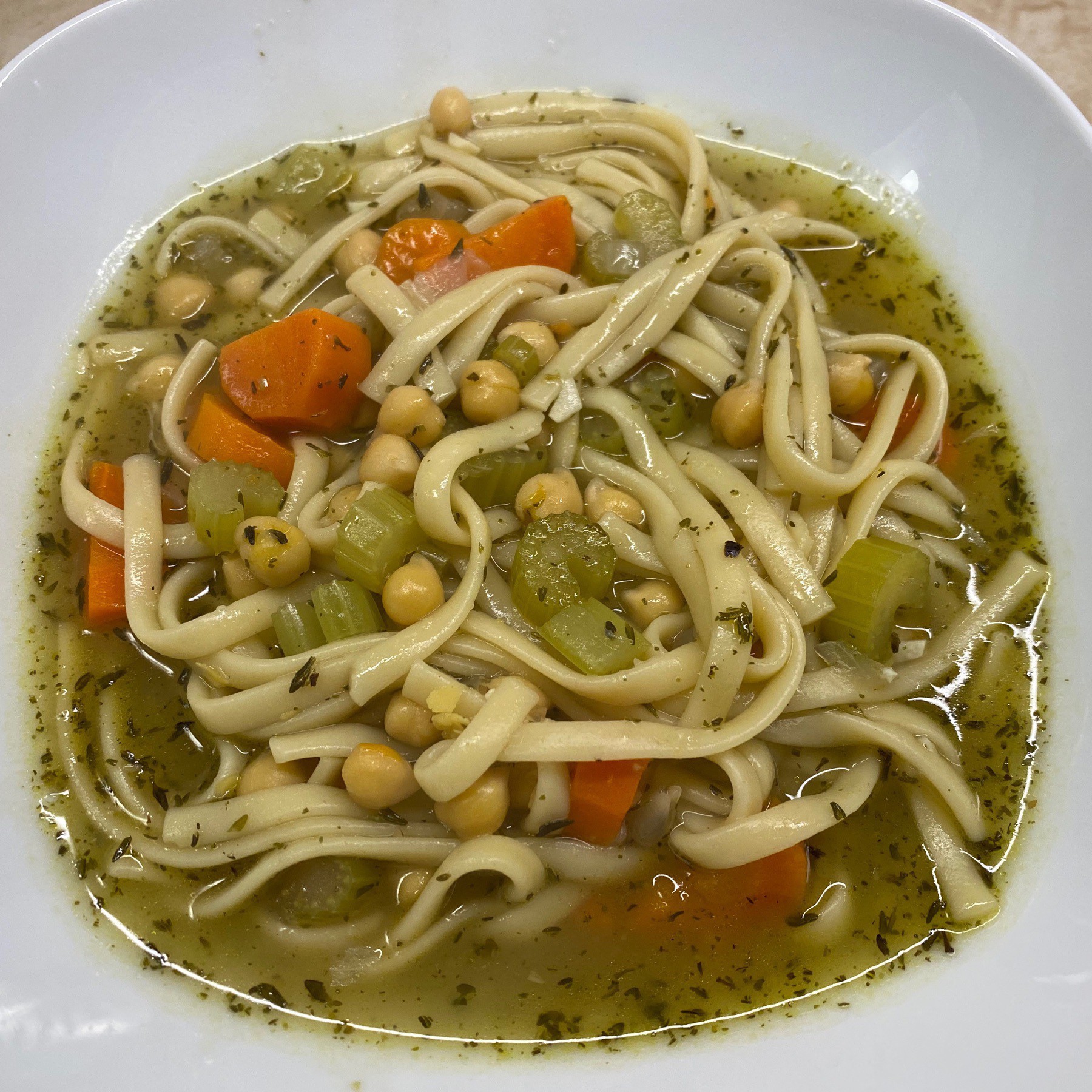 Bowl of soup with noodles, chickpeas, carrots, and celery.