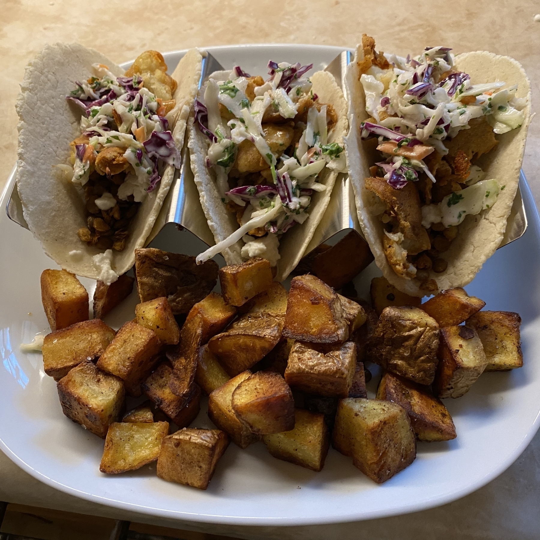 Tacos and fried potatoes on a plate.