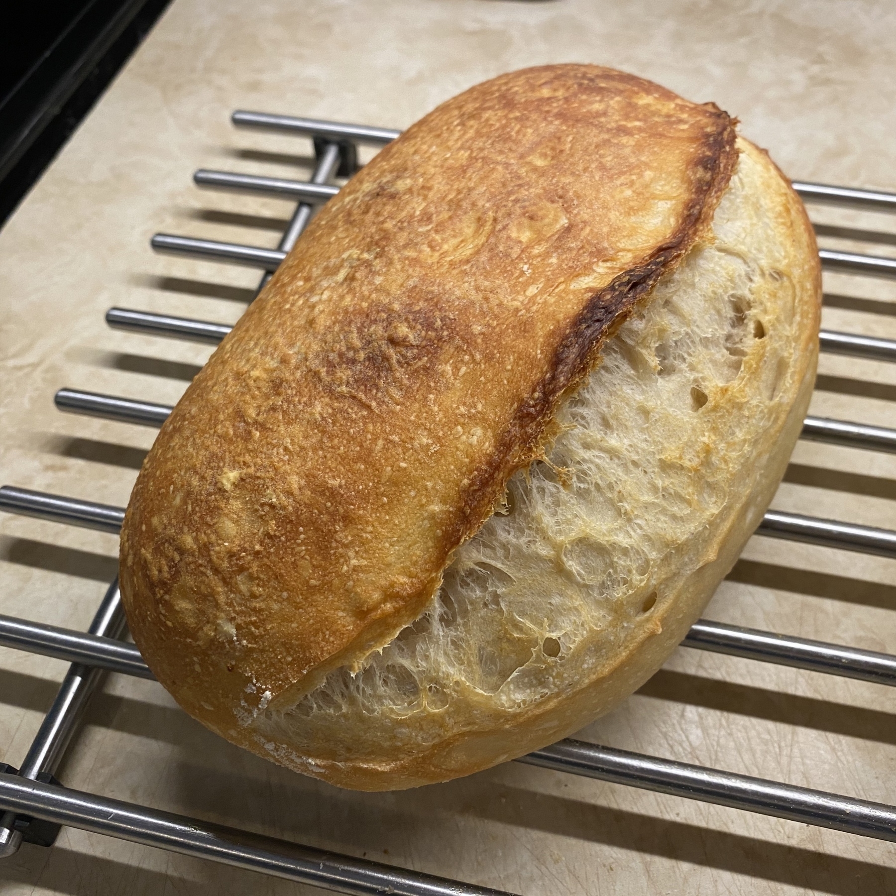 Sourdough loaf of bread on metal rack.
