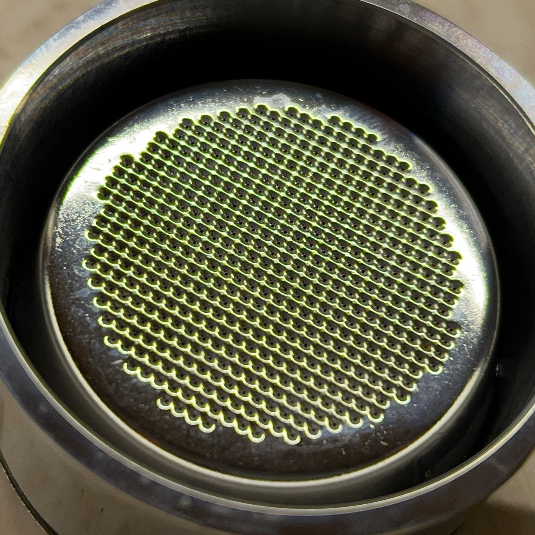 Silver metal espresso filter in filter holder. 