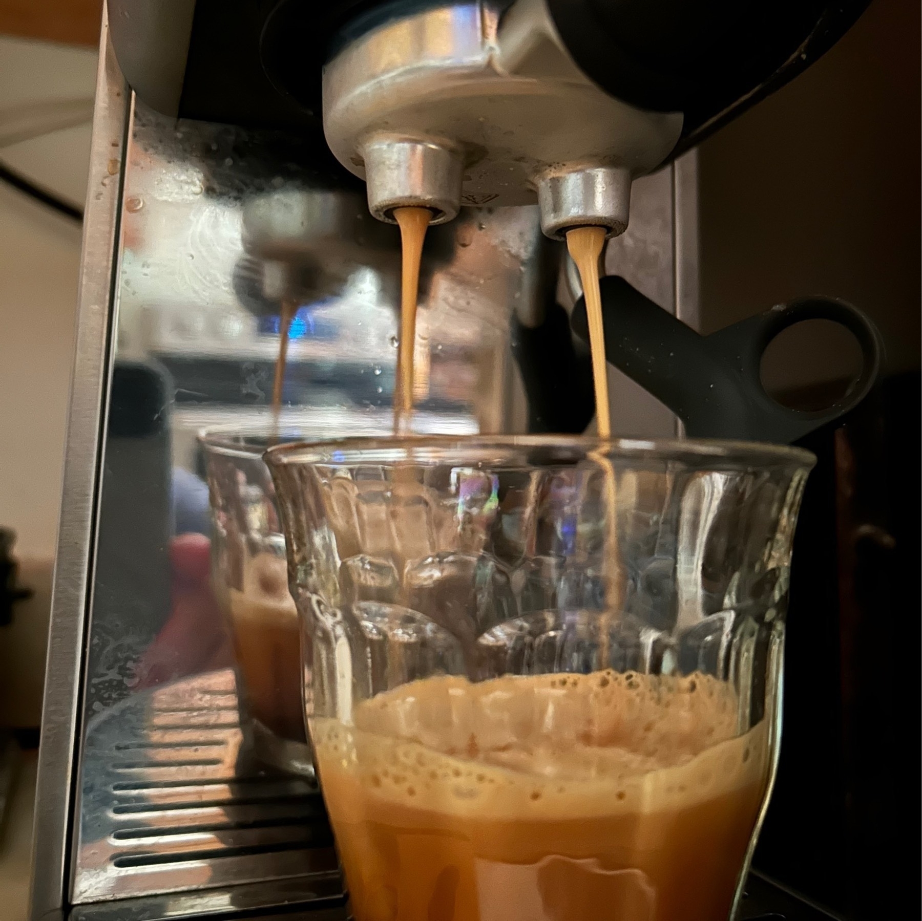 Espresso coming from a portafilter head into a clear glass.
