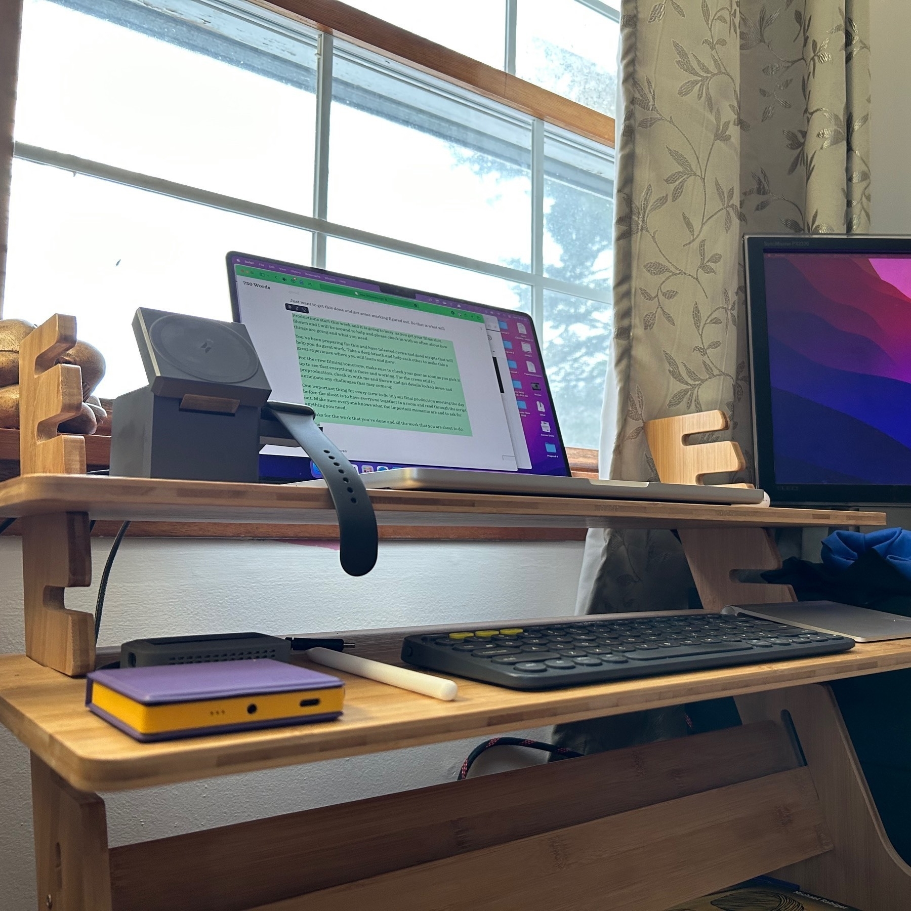 Laptop on wooden support with various accessories around it. 