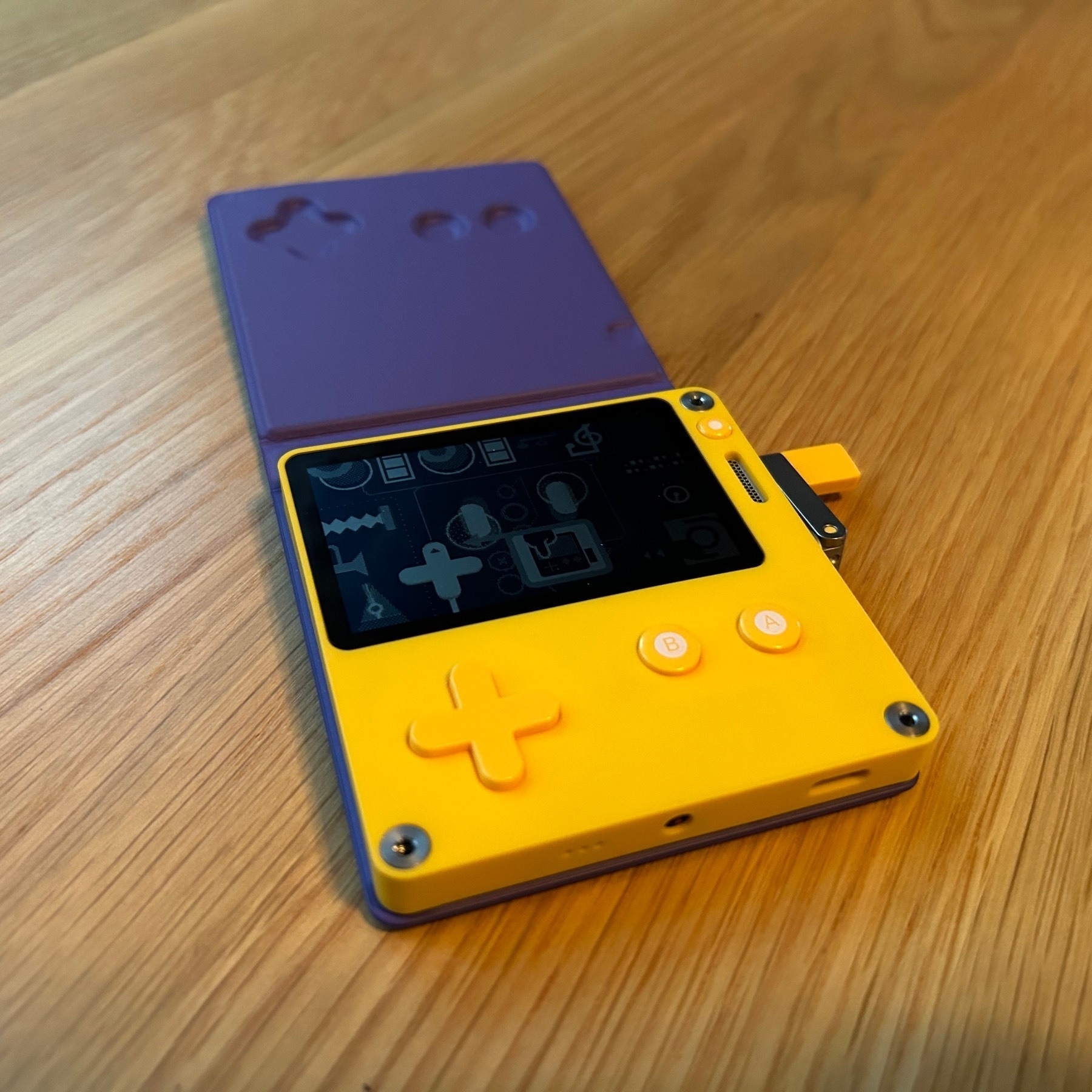 Small yellow and purple play date video game system with LED screen sitting on a wooden table. 